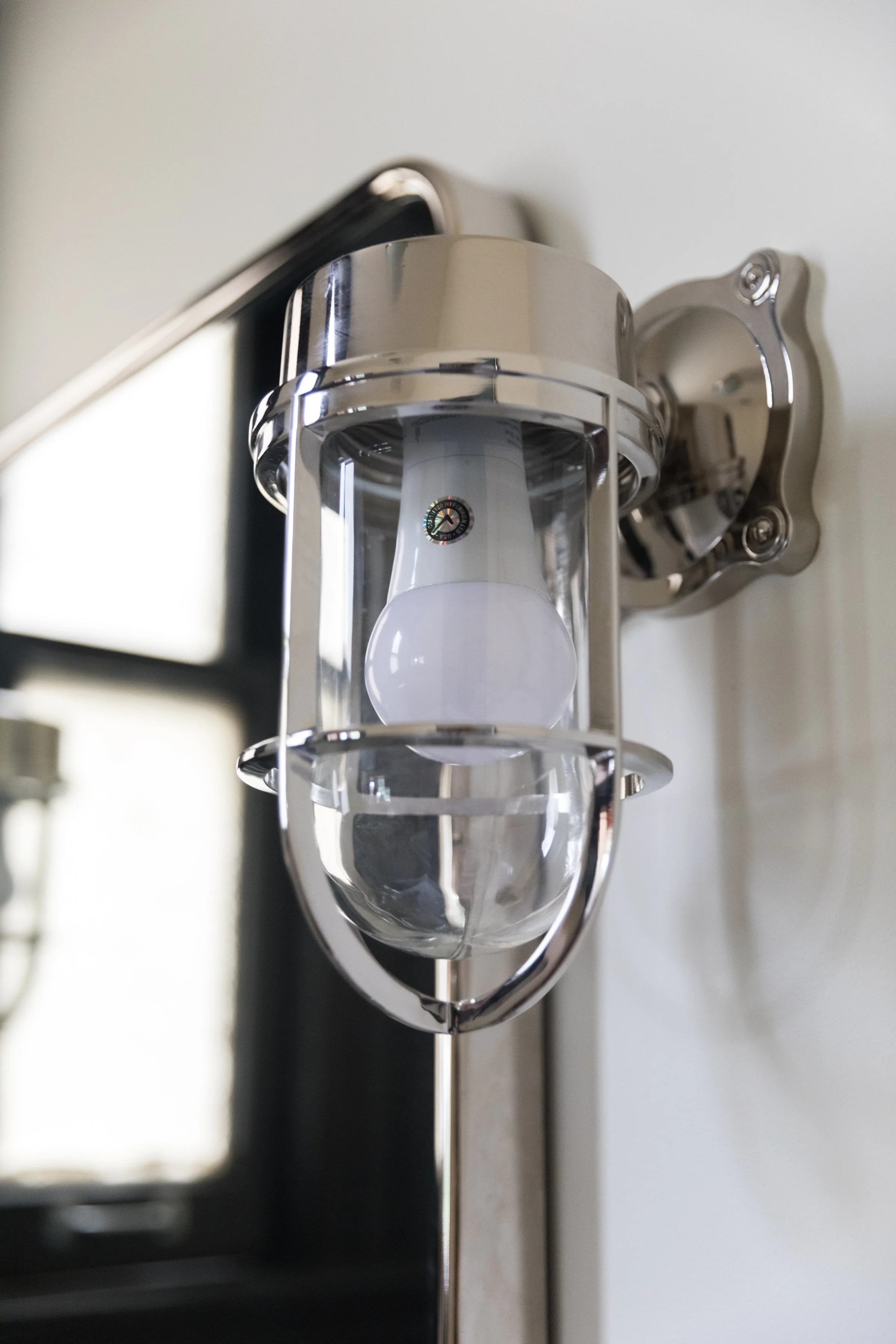 Close-up of a polished nautical-style caged wall sconce beside a window