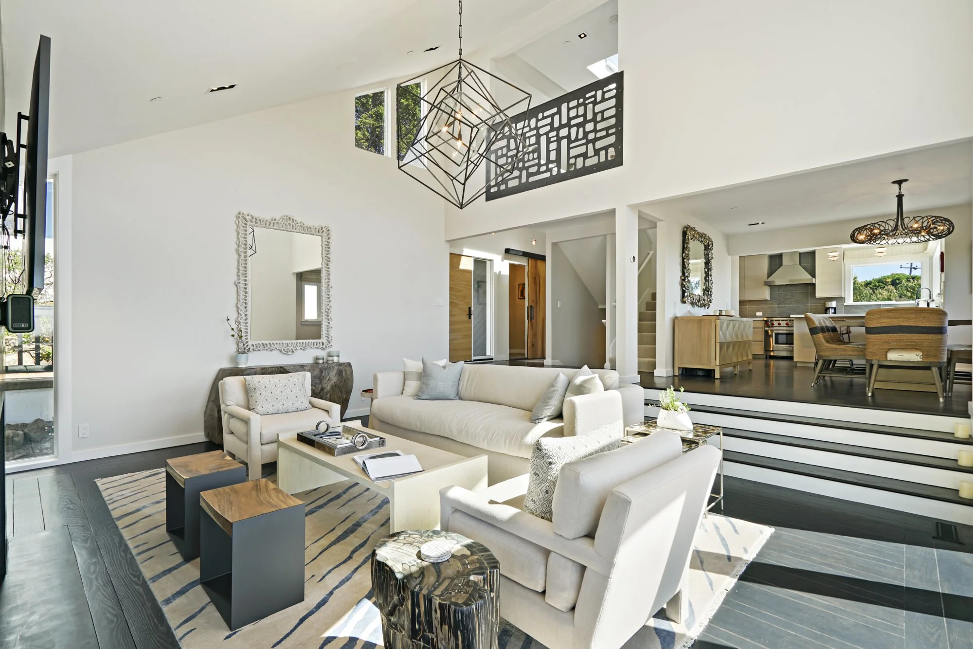 Open living room with a vaulted ceiling, a cream sectional sofa, a modern chandelier, and a view into the dining and kitchen areas