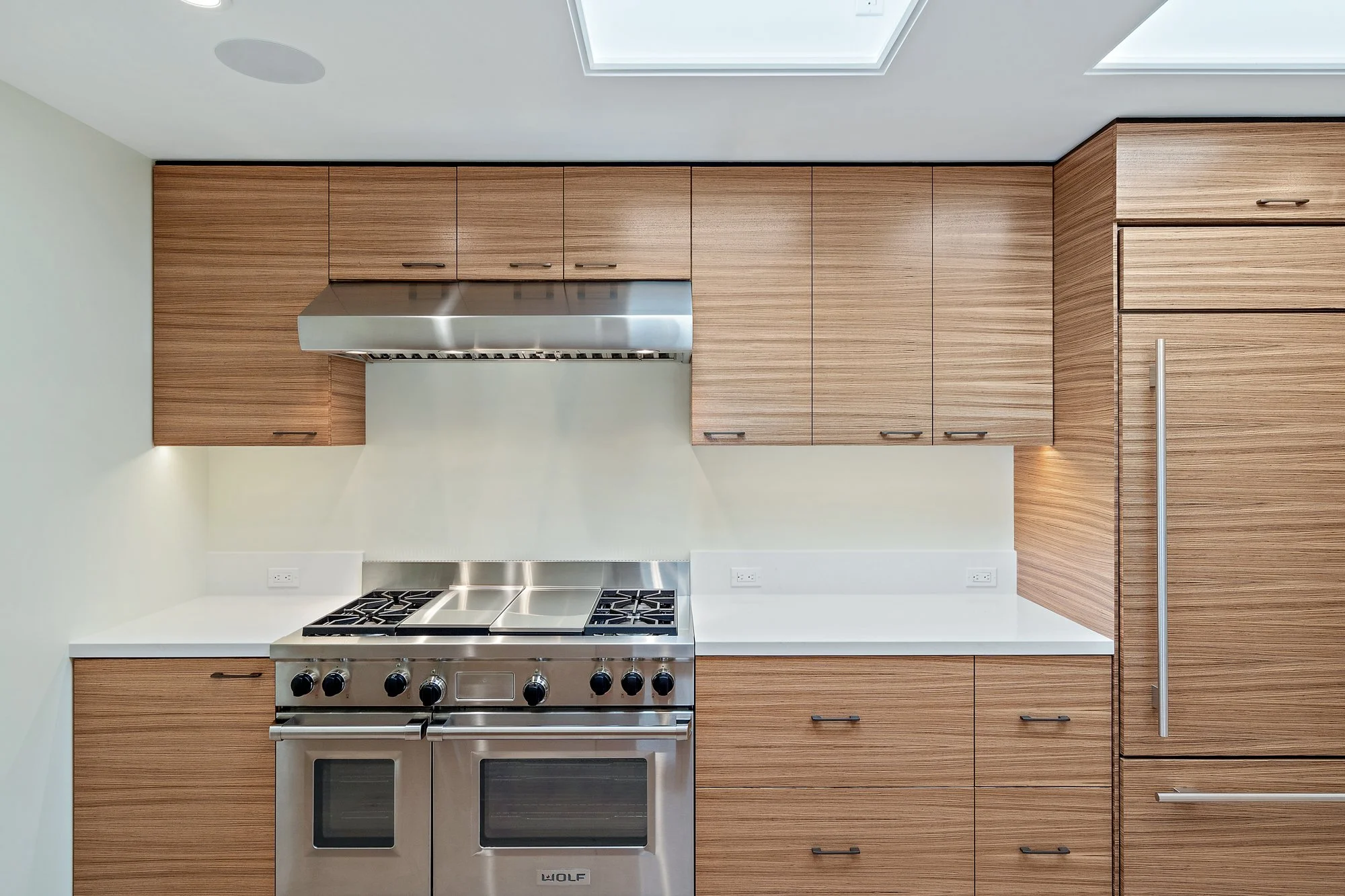 Kitchen with wood-grain cabinetry, a stainless gas range with double ovens, white countertops, and a paneled refrigerator