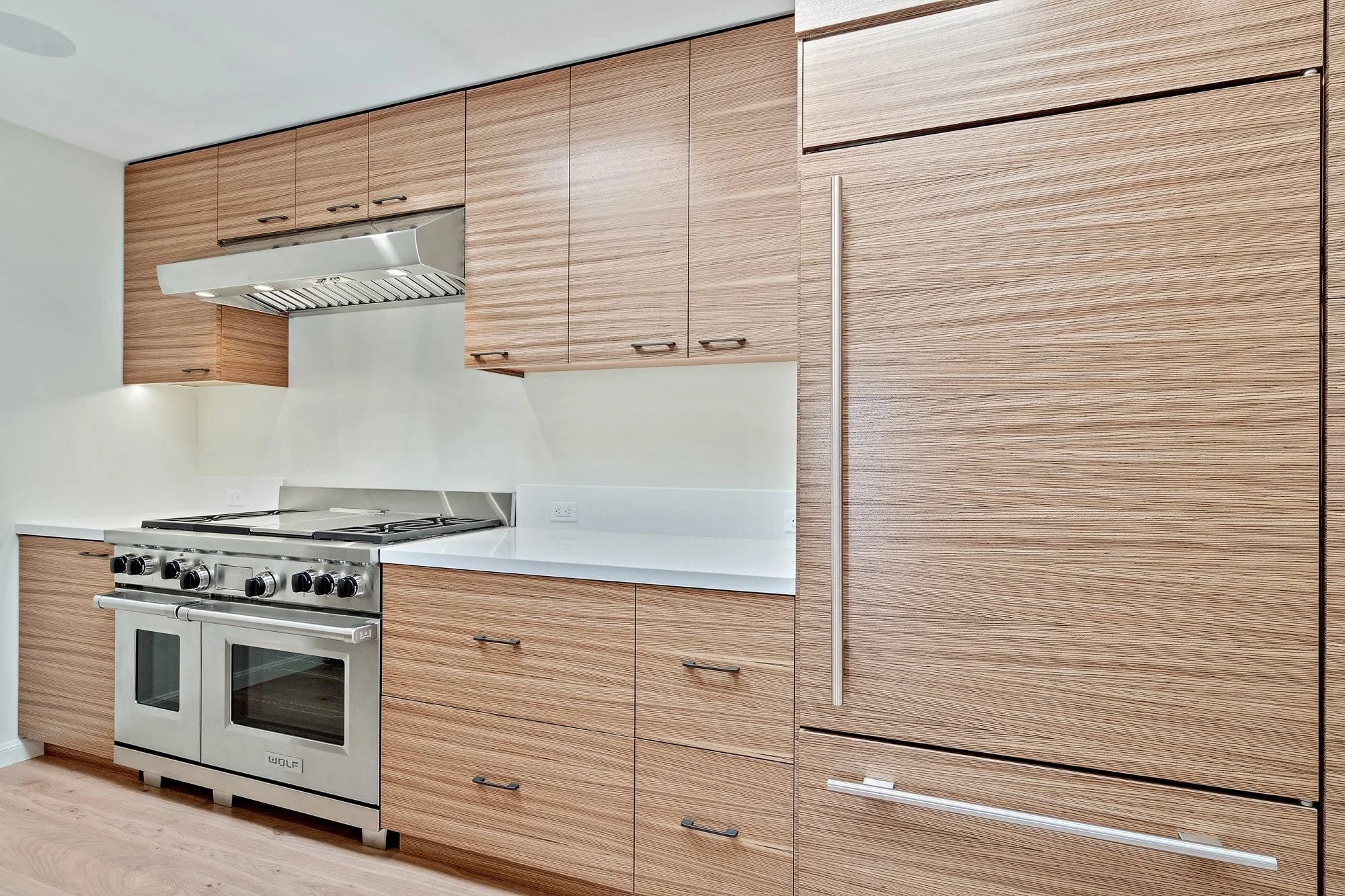 Kitchen with wood-grain cabinets and a paneled refrigerator, professional stainless double-oven range, and white countertops