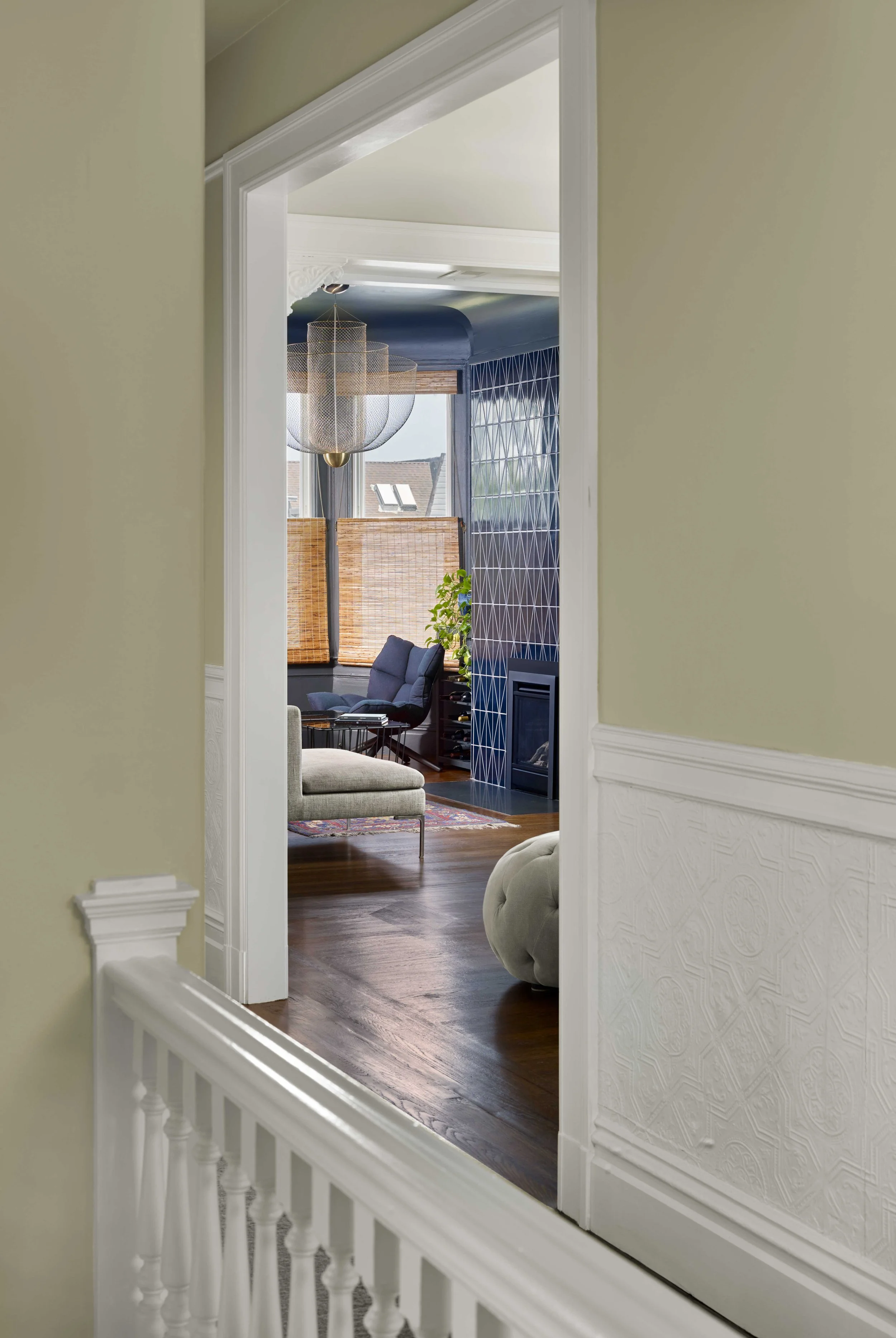 Upstairs landing with white wainscoting and a banister, looking into a sunlit room