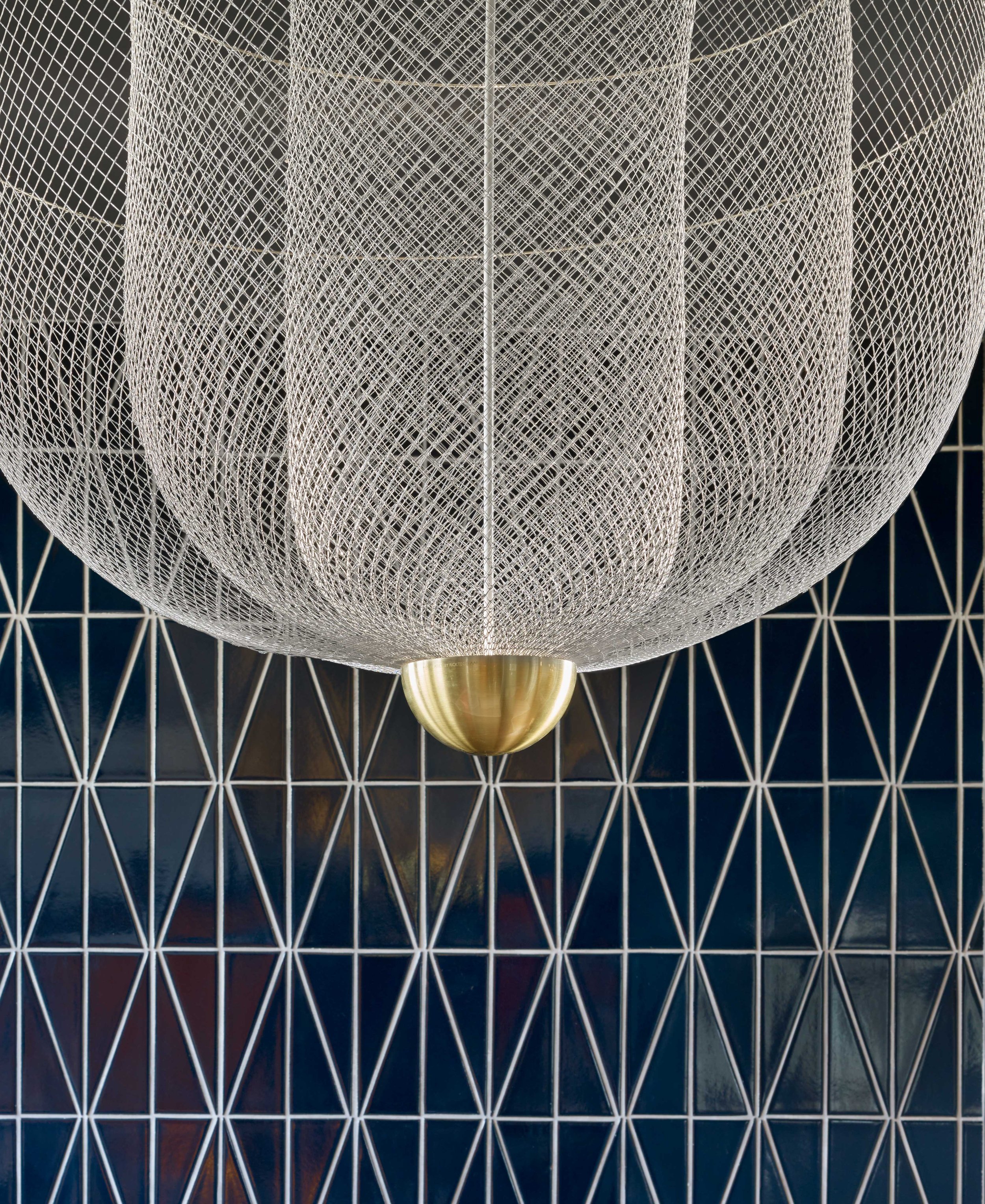 Close-up of a woven pendant light hanging above blue geometric tile