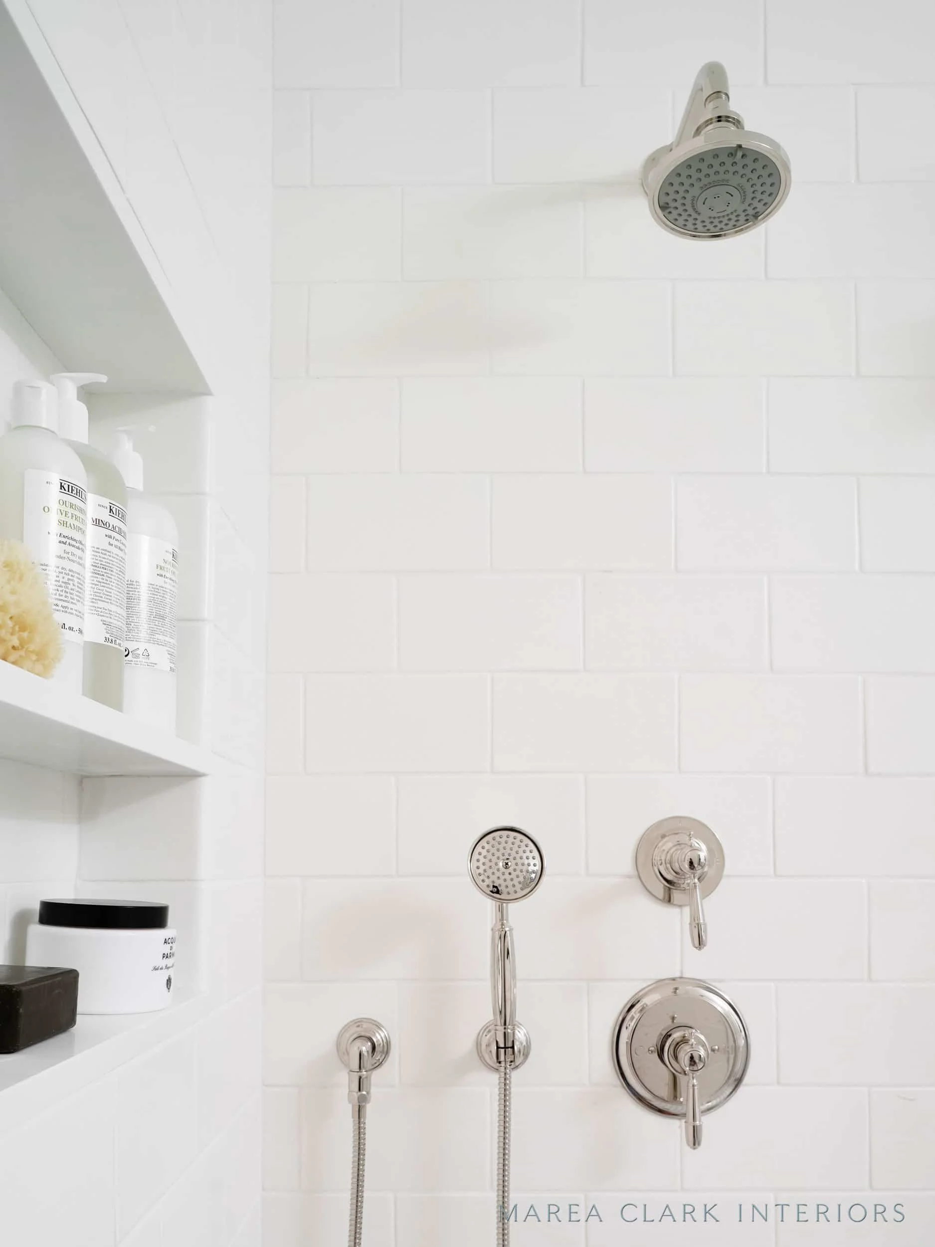 White subway-tiled shower with a recessed niche, rain showerhead, and polished nickel controls
