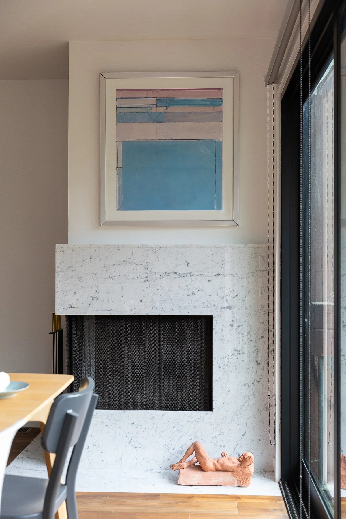 Dining nook with a marble fireplace, framed coastal artwork, and a sliding glass door