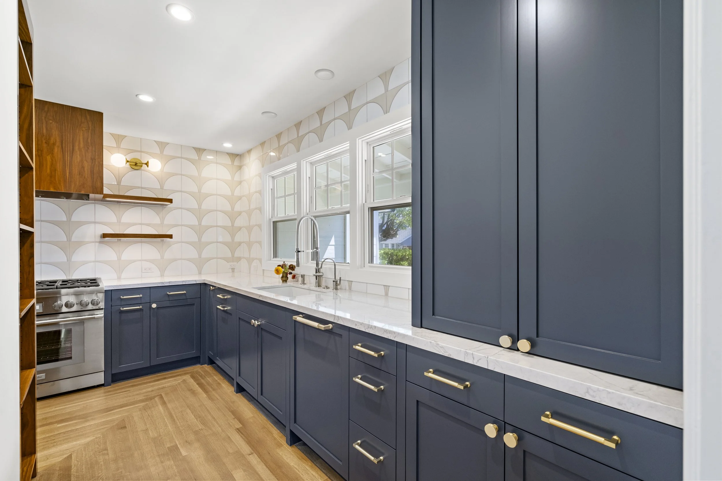 Kitchen with navy cabinets, white countertops, a scalloped tile backsplash, wood shelving, and a stainless range