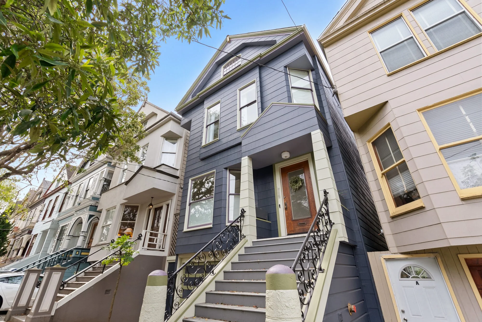 Exterior of a blue Victorian home with bay windows, ornate trim, and an entry staircase