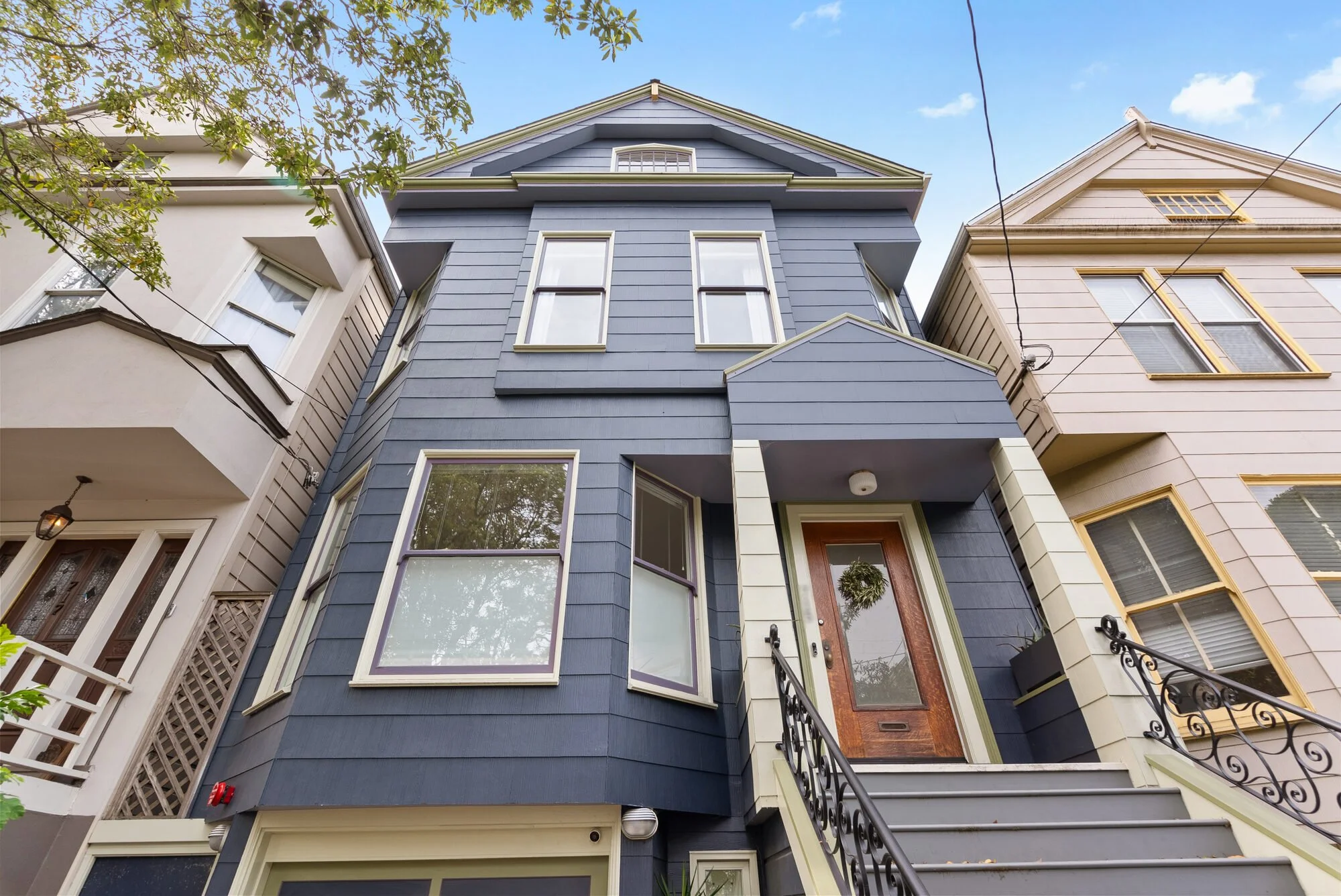 Exterior view of a blue Victorian home with bay windows and light-colored trim