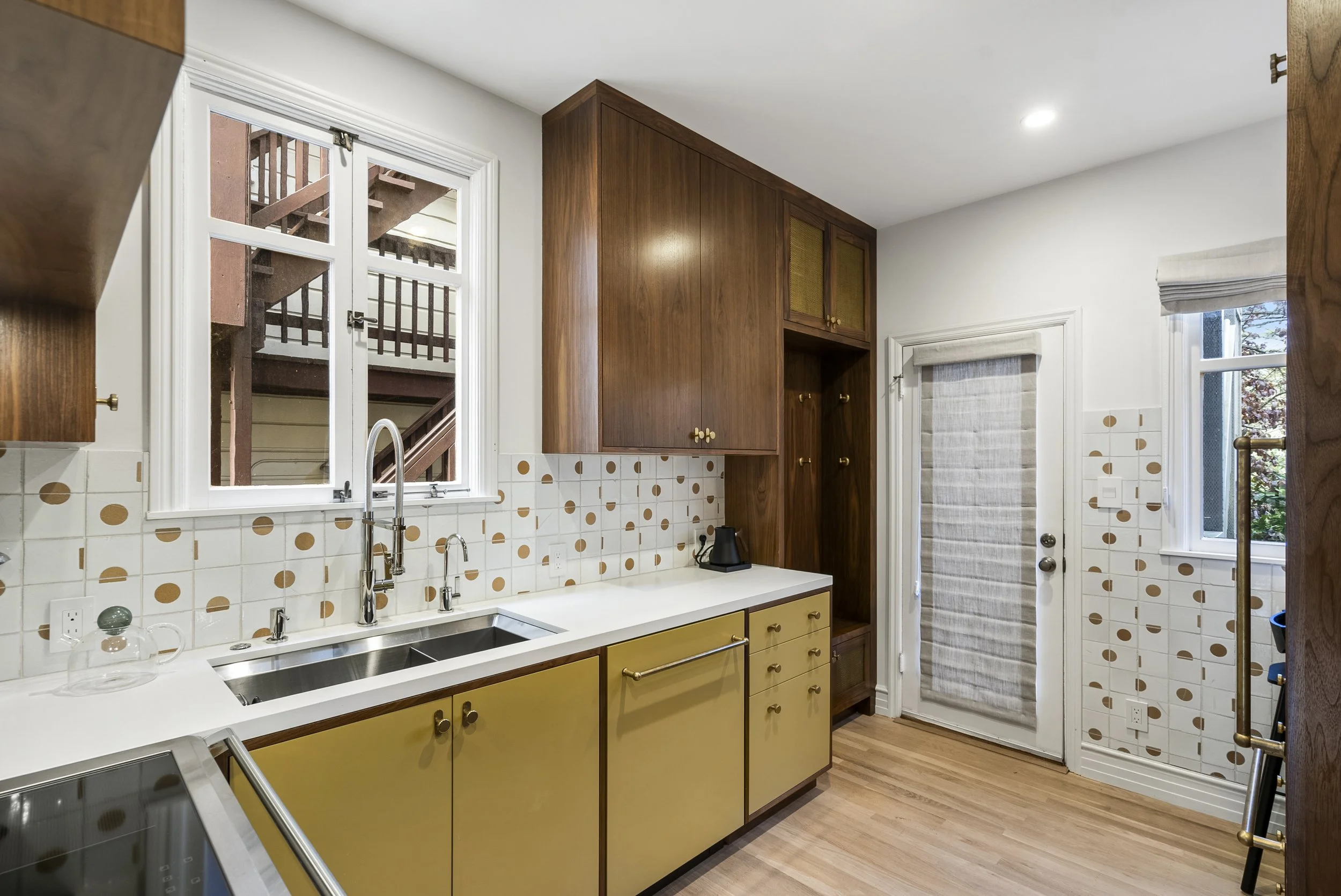 Kitchen with olive-green cabinets, walnut cabinetry, white and gold penny tile backsplash, and a glass door