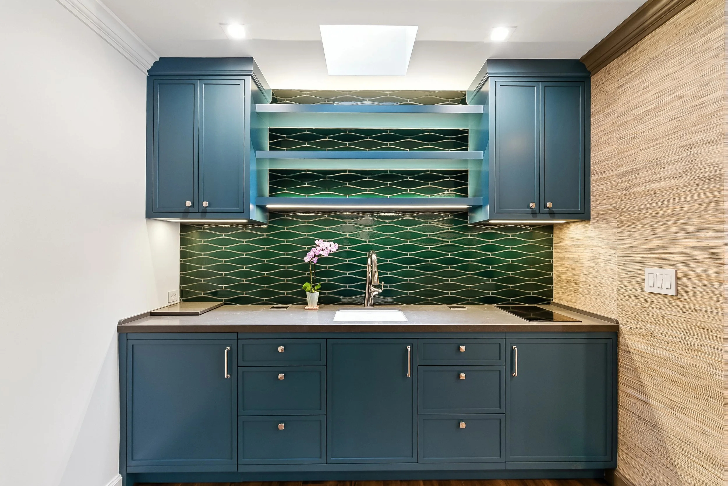 Wet bar area with navy blue cabinets, a green tile backsplash, and open shelving