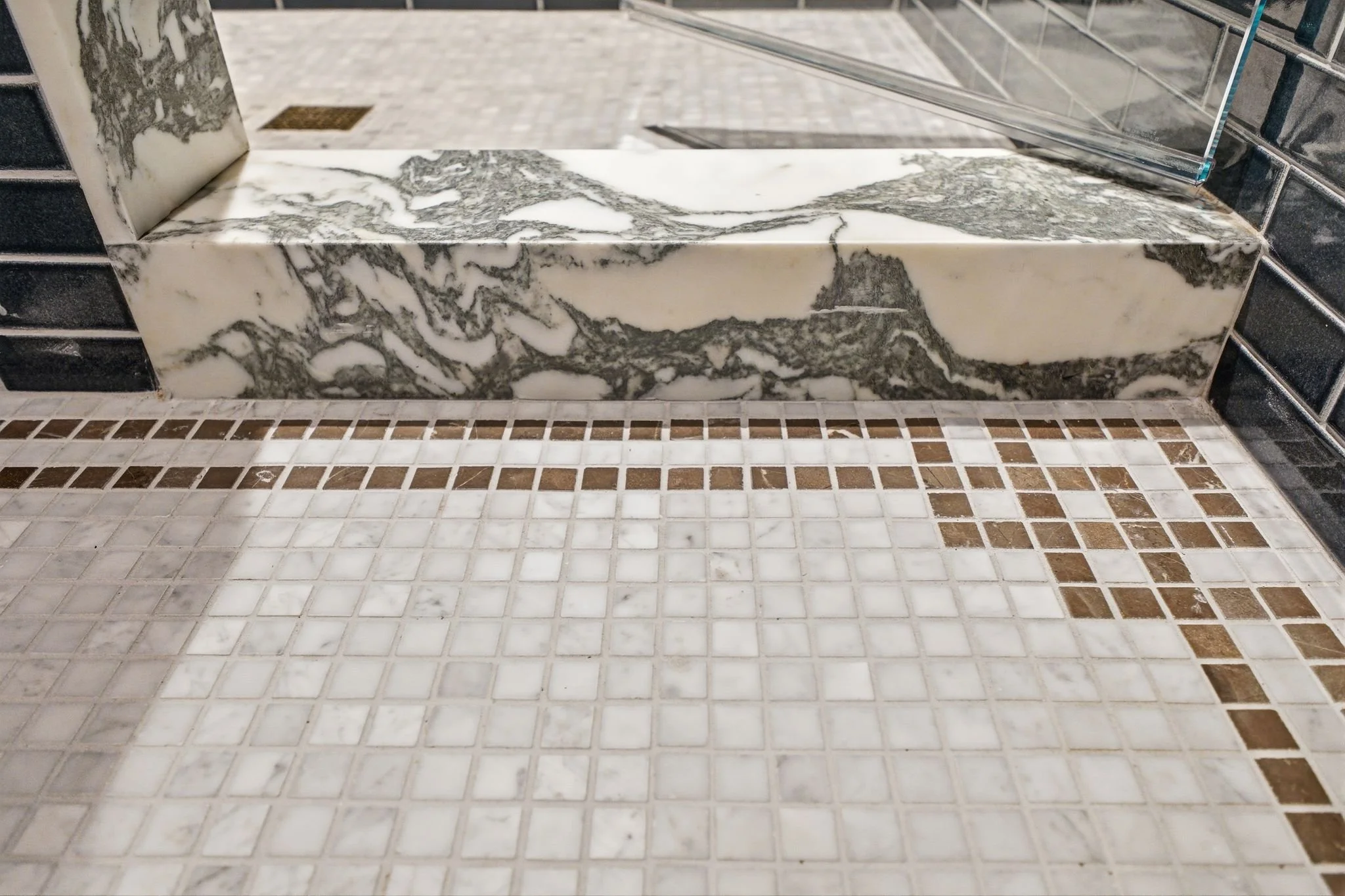 Marble soaking tub area with a checkered marble and bronze mosaic tile floor