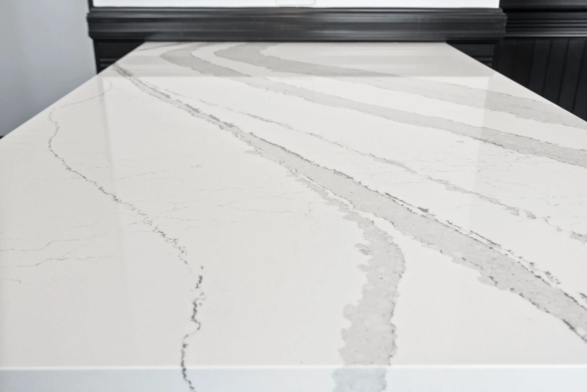 Close-up of white quartz countertop with gray veining and black window trim