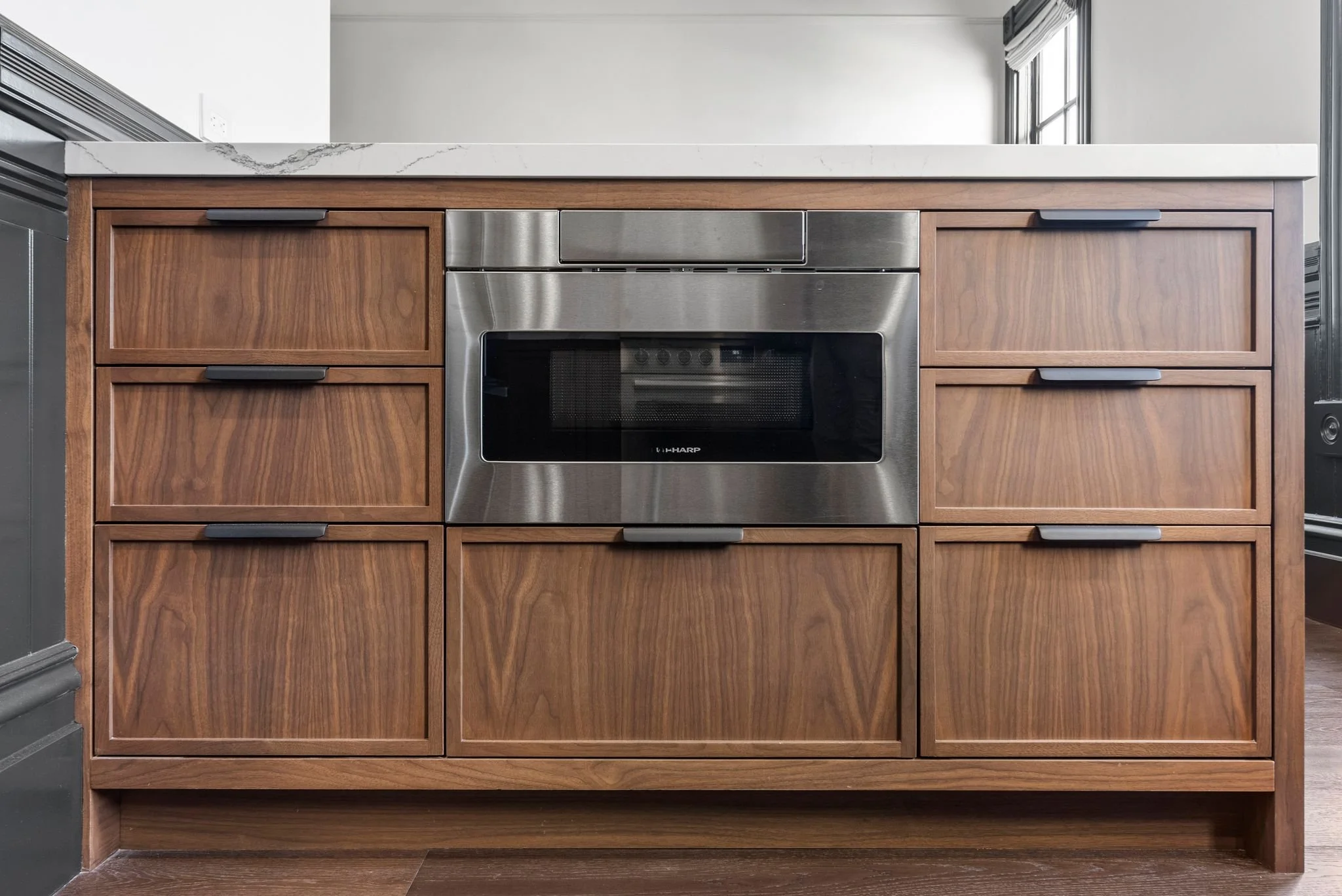 Walnut kitchen island with integrated microwave drawer, black pulls and quartz top