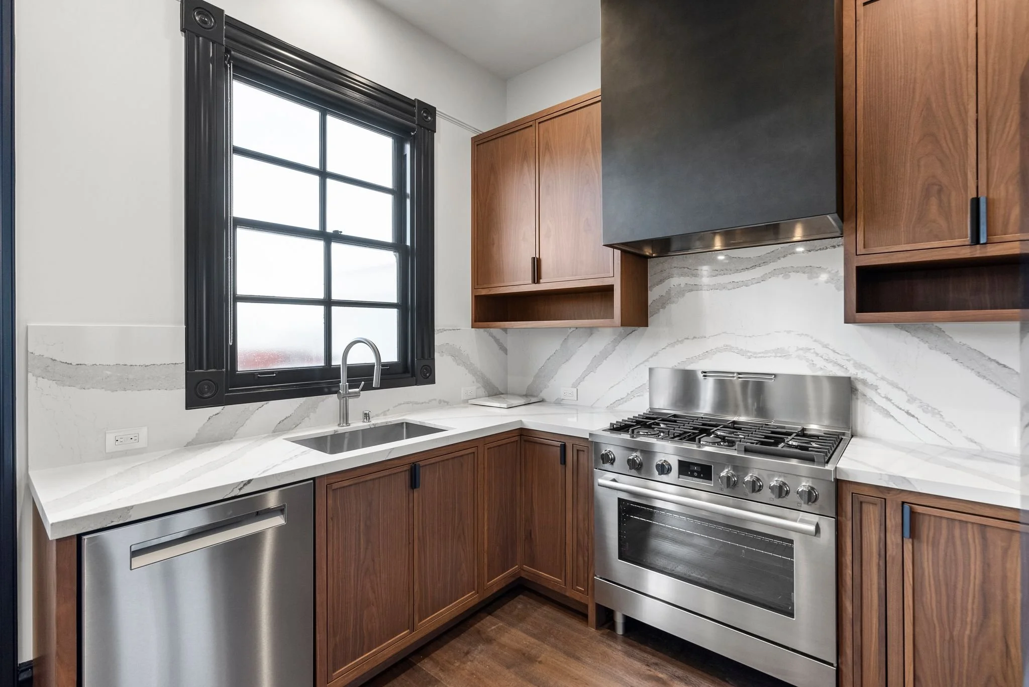 Kitchen corner with undermount sink, stainless dishwasher, pro-style range and full-height quartz backsplash