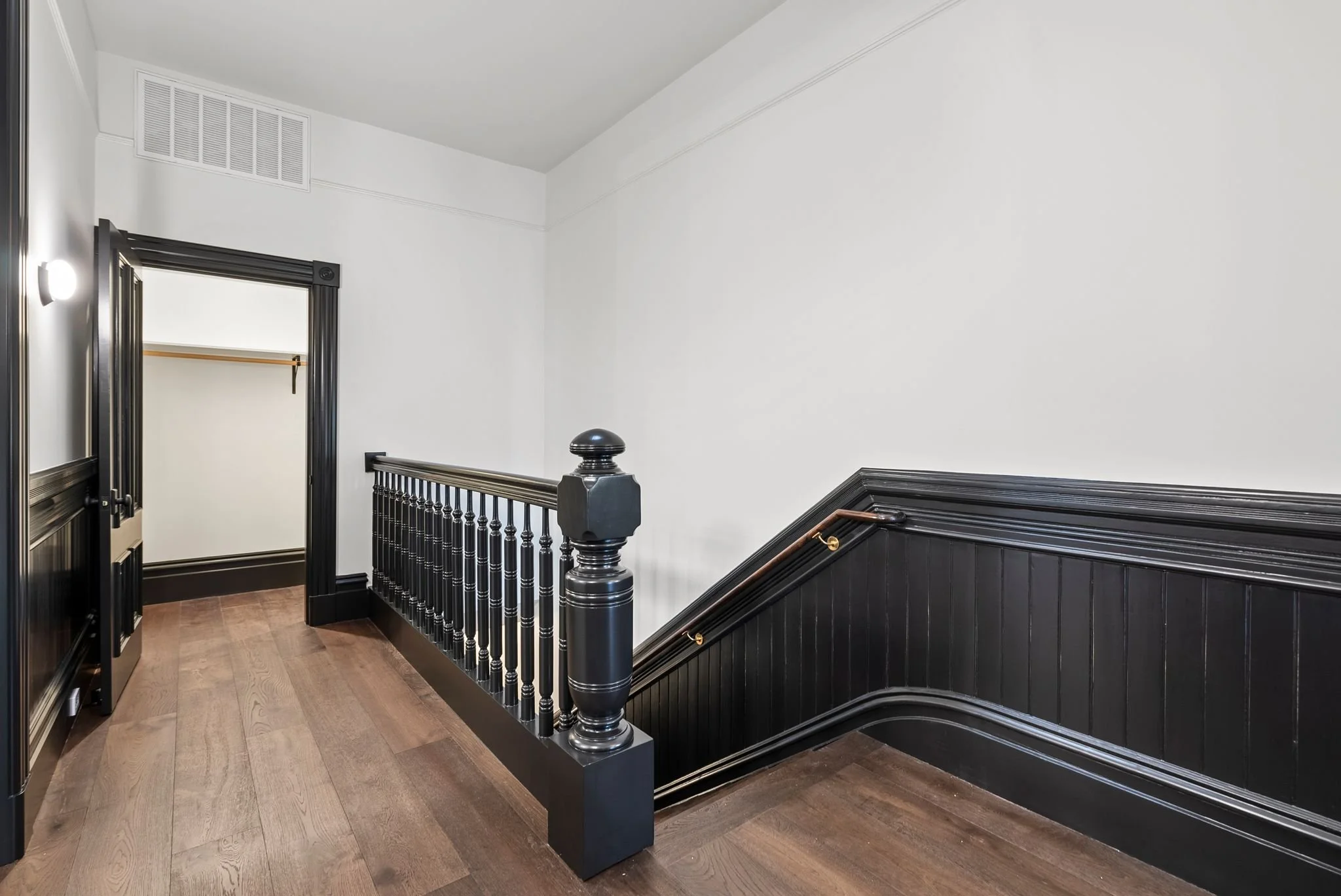 Upper landing with black turned balusters, newel post and beadboard wainscoting