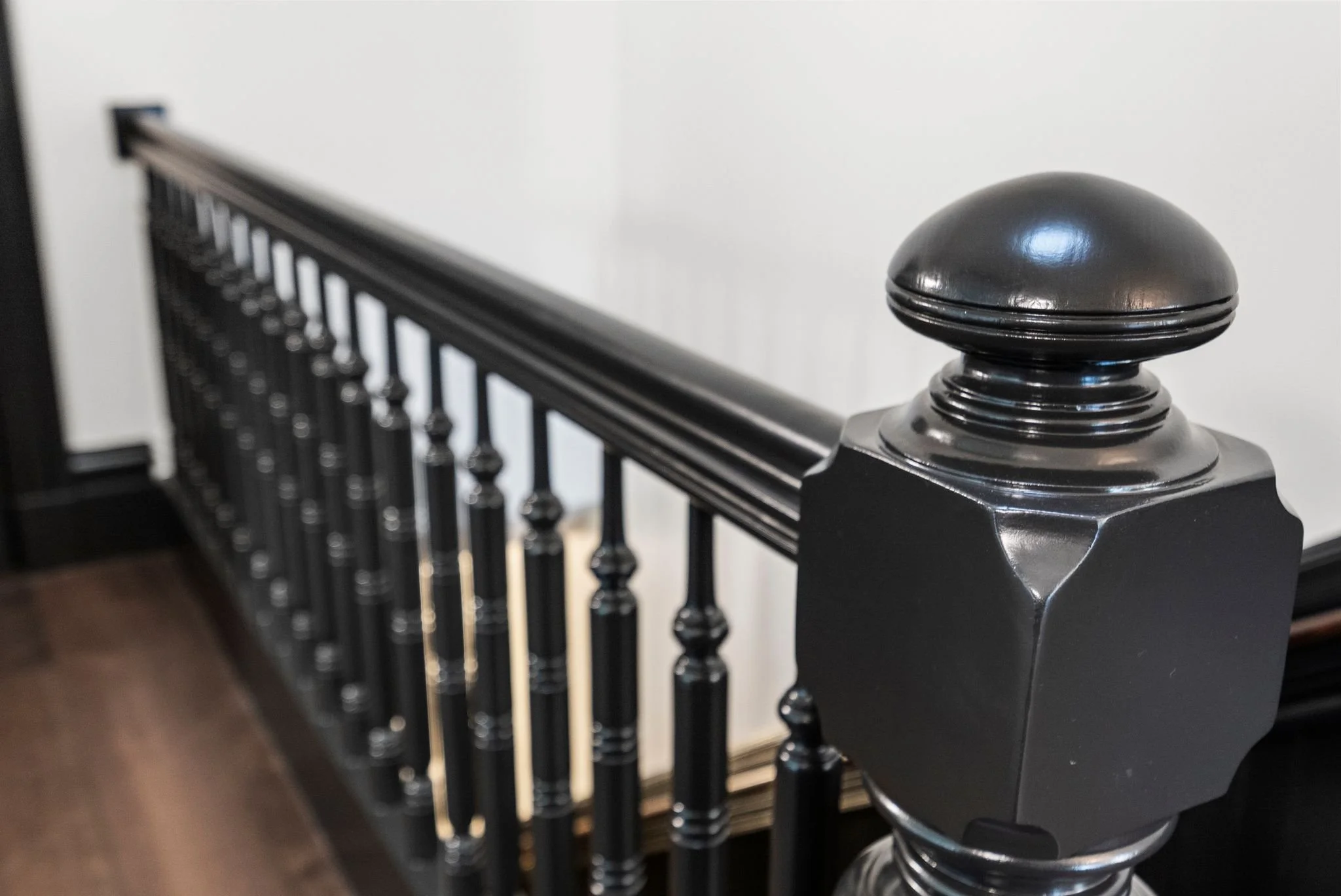 Close-up of black-painted turned newel post and stair balusters
