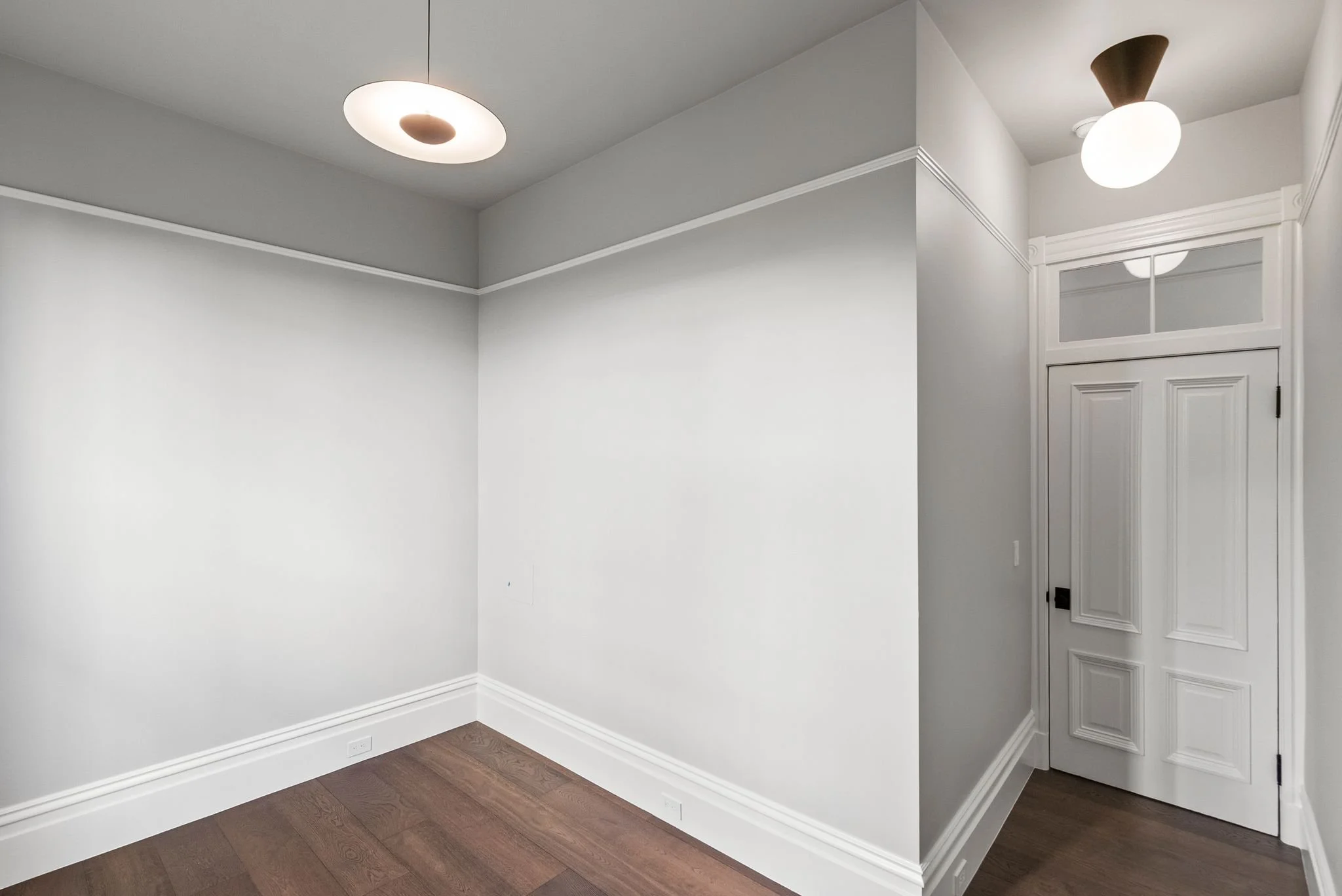 Bedroom corner with picture rail, oak floors and round flush-mount ceiling light