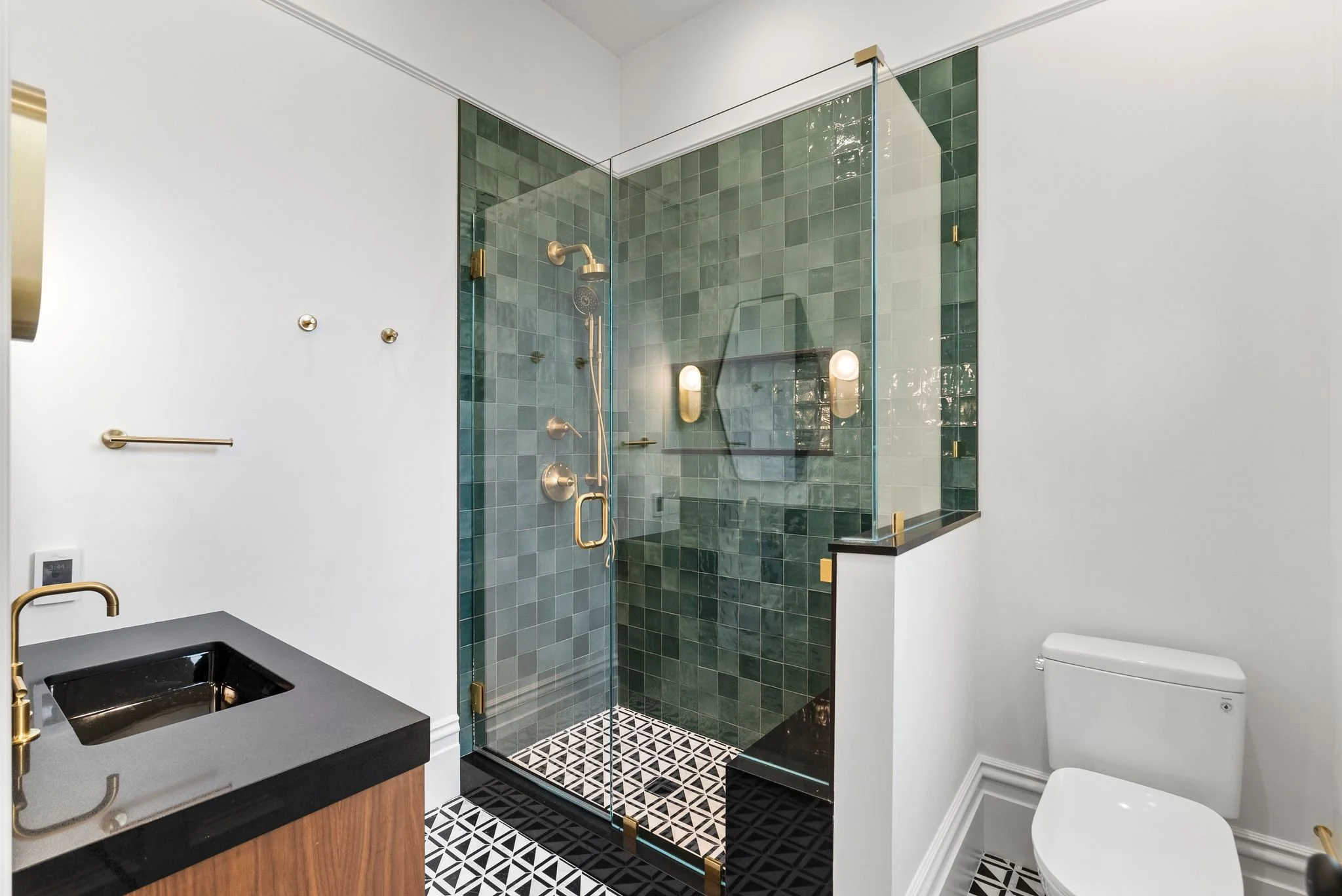 Bathroom with green zellige-tiled walk-in shower, black quartz vanity and brass fixtures