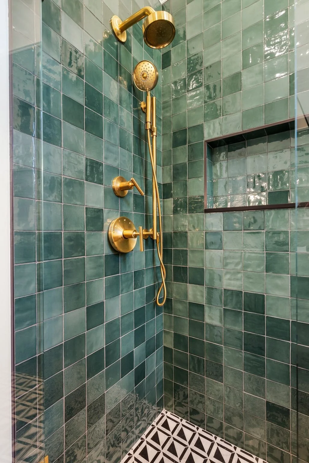 Walk-in shower with green handmade tile, brass rain shower head and hand shower