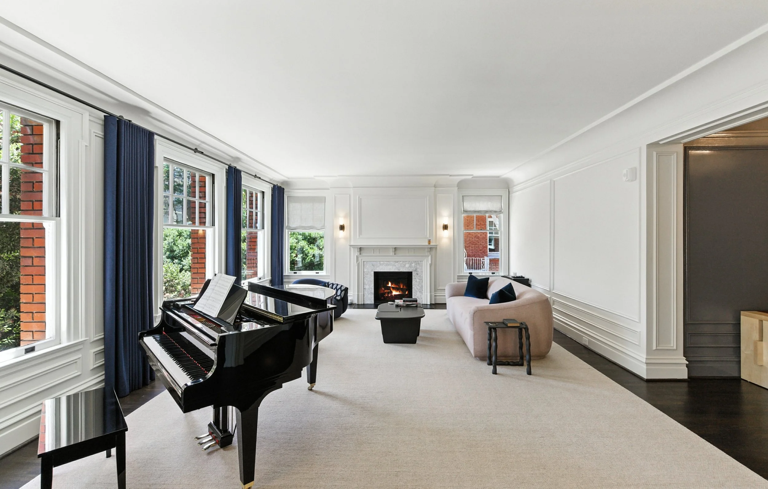 Elegant Pacific Heights living room with a black grand piano, white marble fireplace, navy drapes, and dark hardwood floors