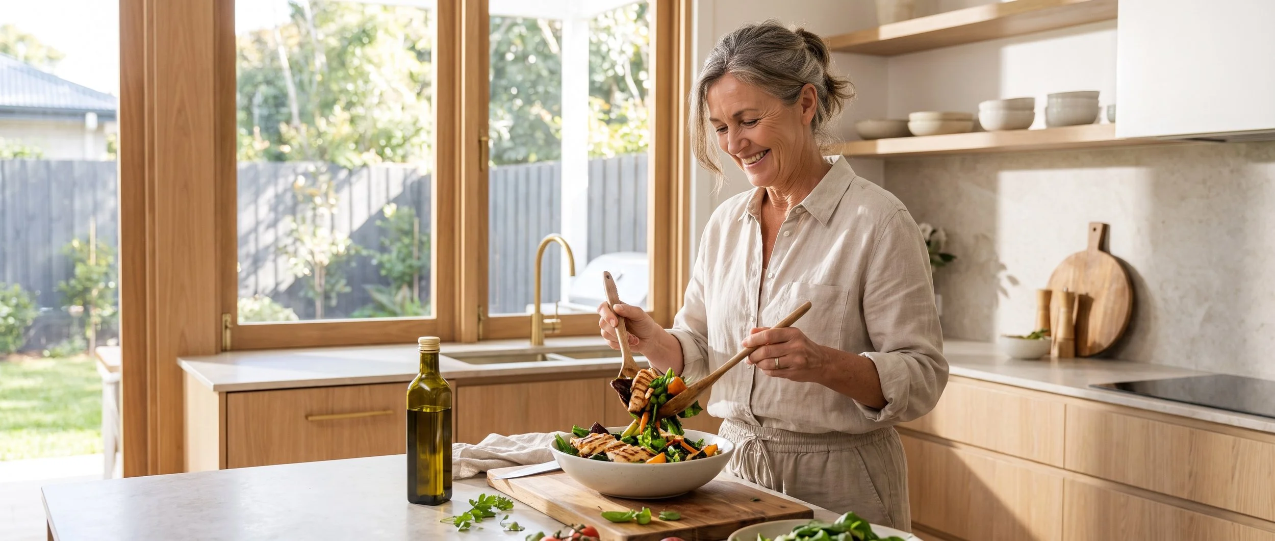Older woman preparing a healthy high-protein salad in a modern kitchen to support muscle health and healthy ageing.