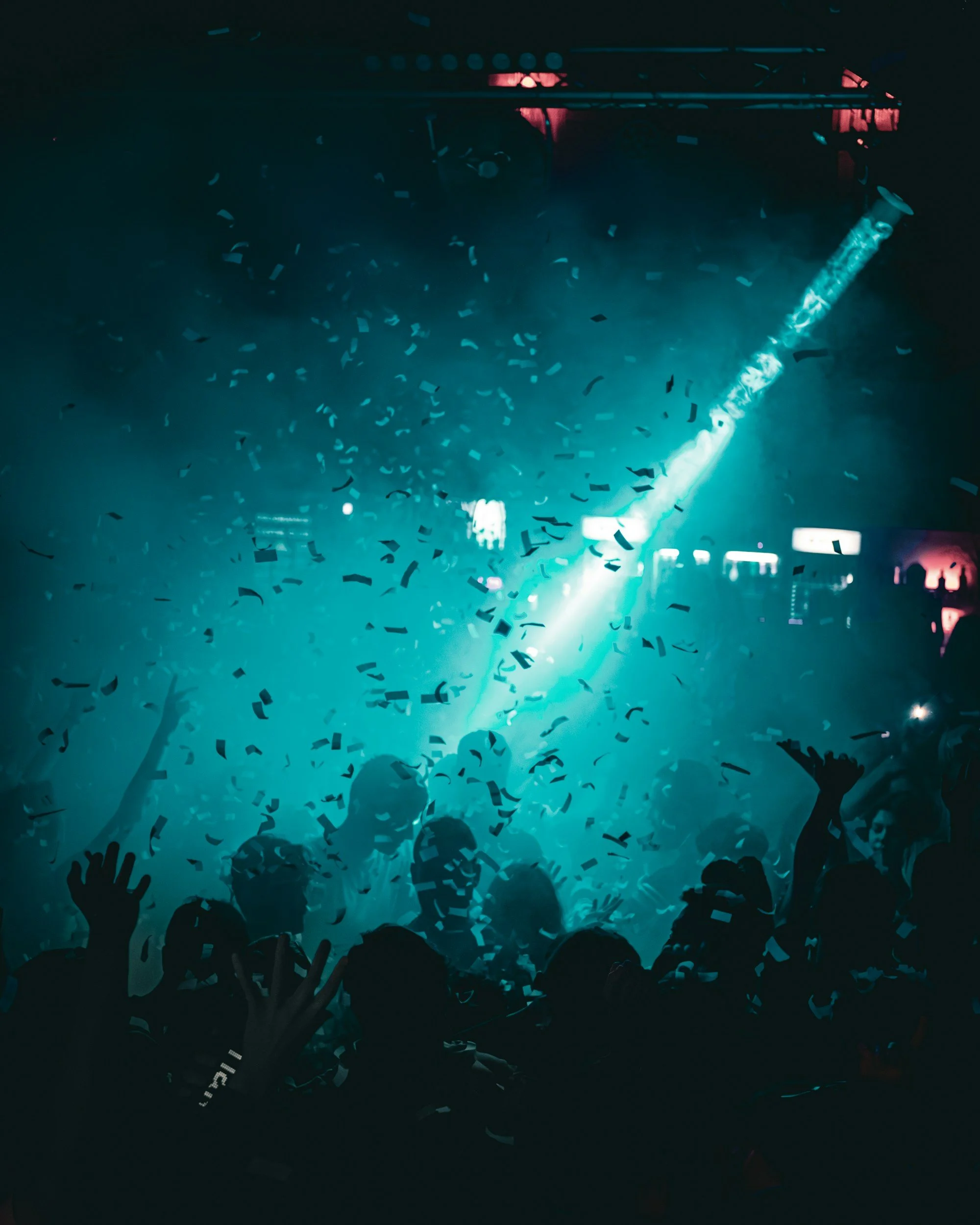 Nightclub crowd dancing under teal lights and confetti