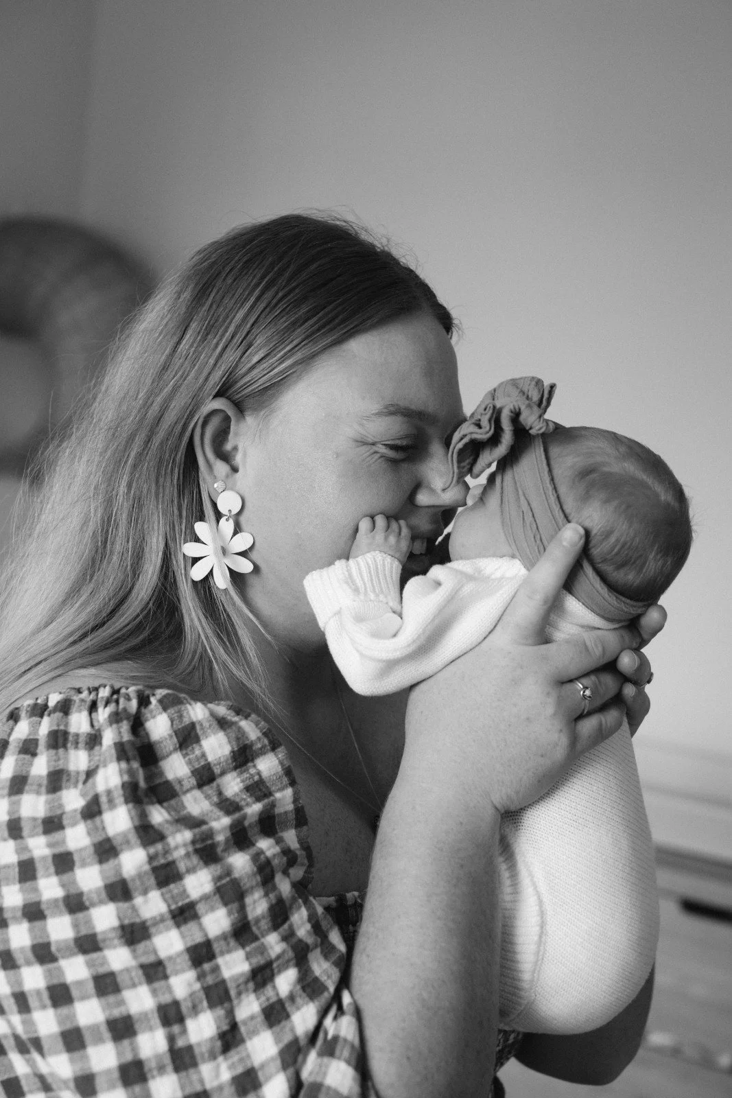 A woman holding a baby close, both smiling and touching foreheads, in a loving embrace.