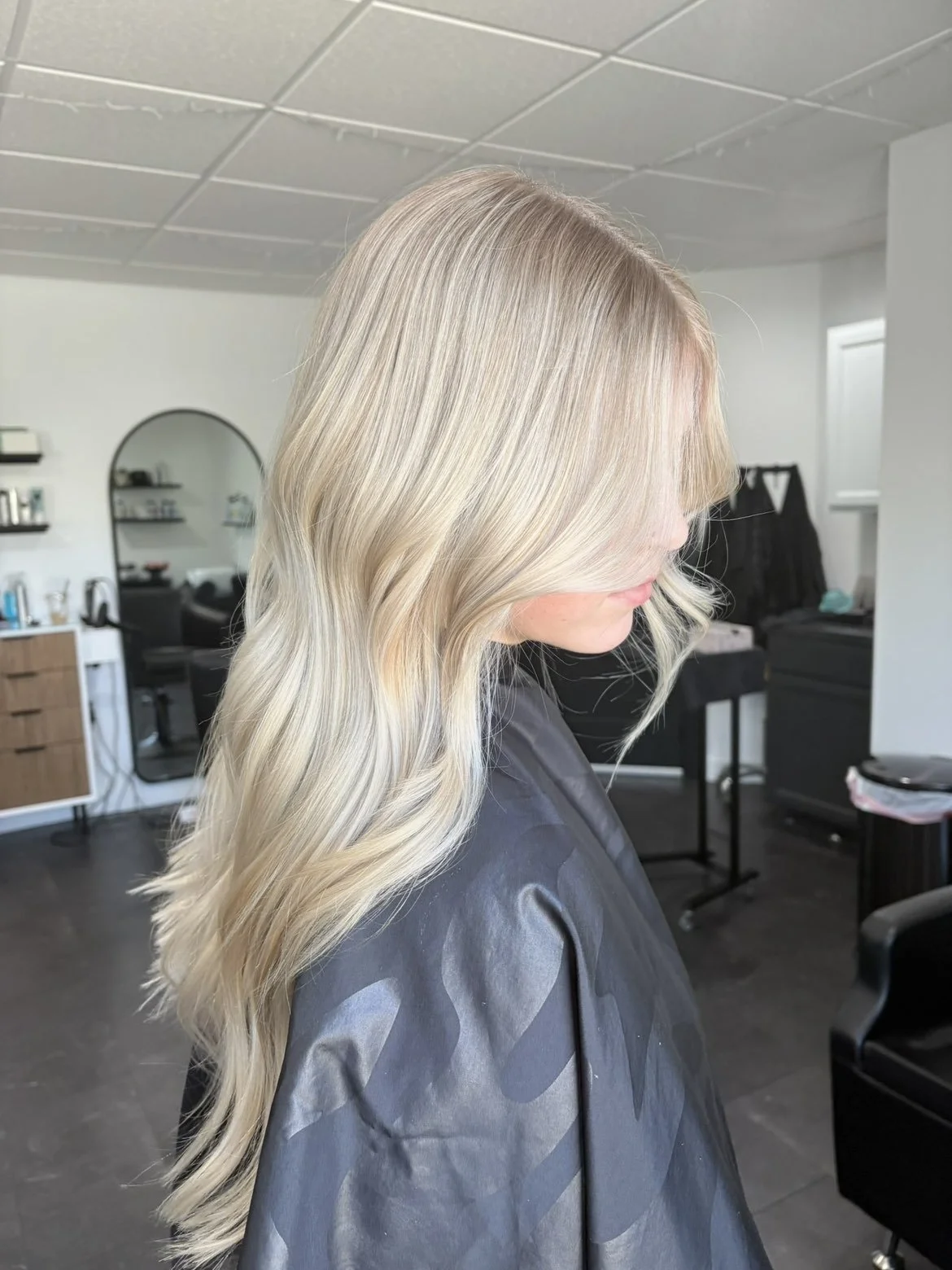 Side view of a woman with long, wavy blonde hair in a salon or studio.
