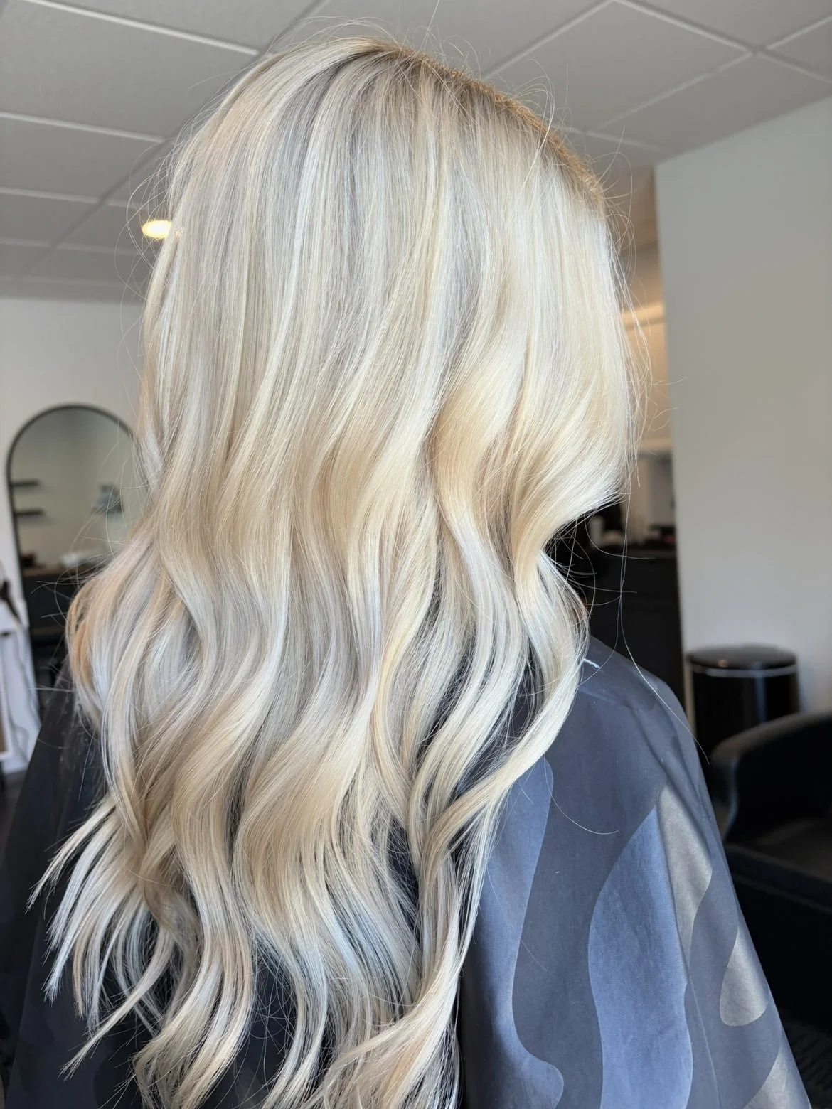 Blonde wavy hair seen from the side in a salon setting.