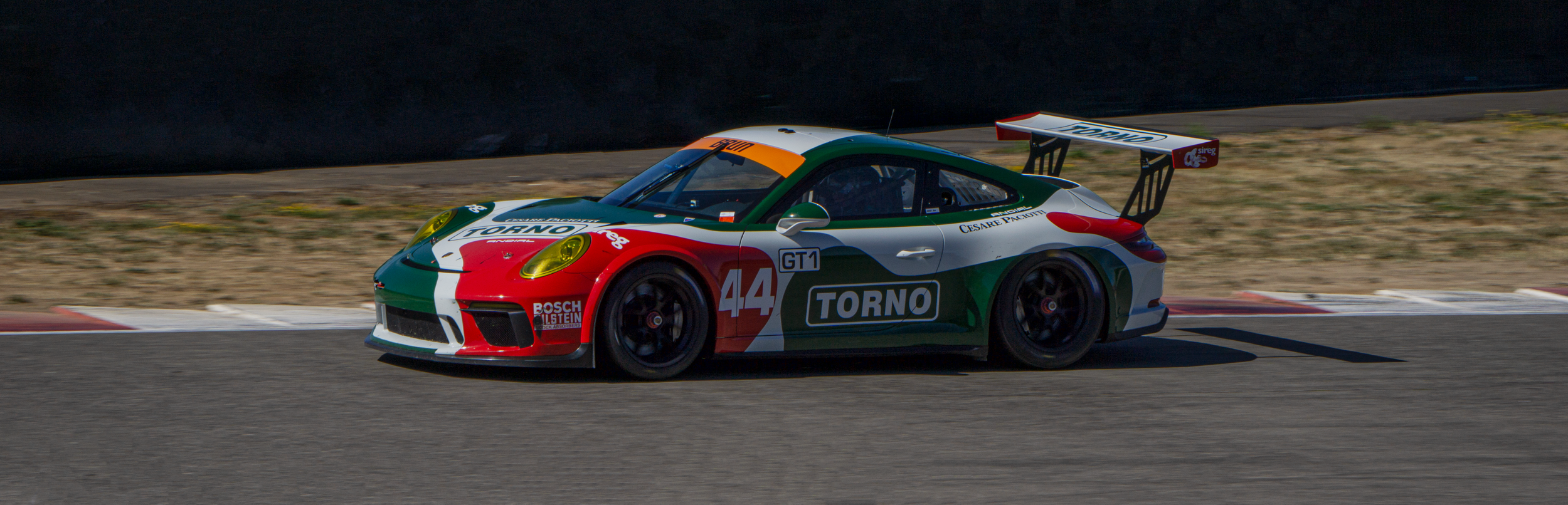 Race car on track with sponsors and number 44, green, red, and white livery, large rear wing.