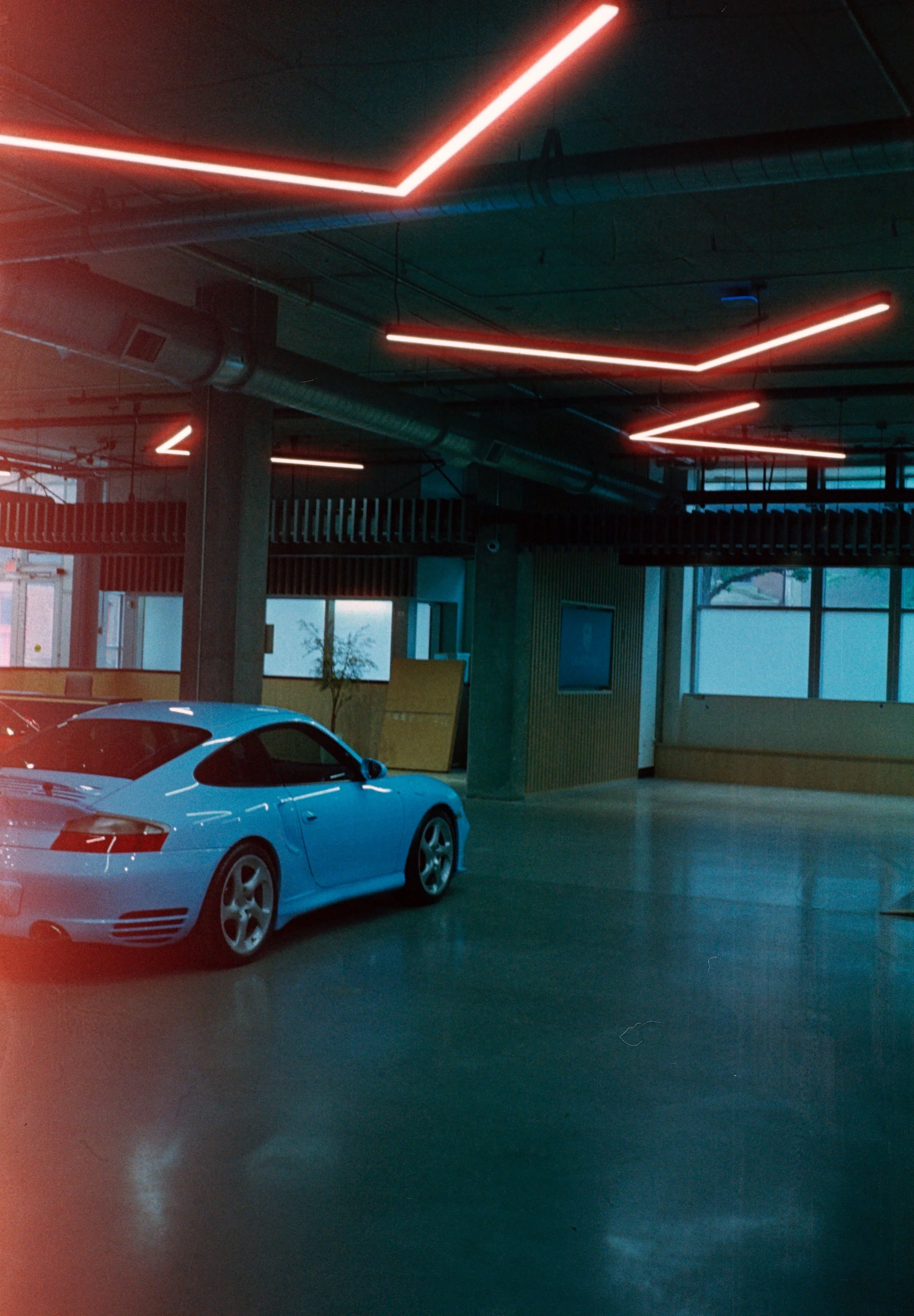An indoor parking garage with modern lighting and a white car parked in the foreground.