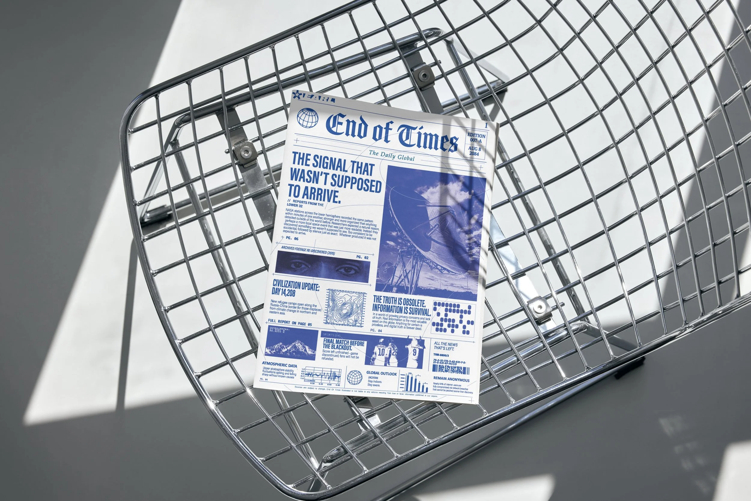 A shopping cart with a newspaper in it on a gray surface.
