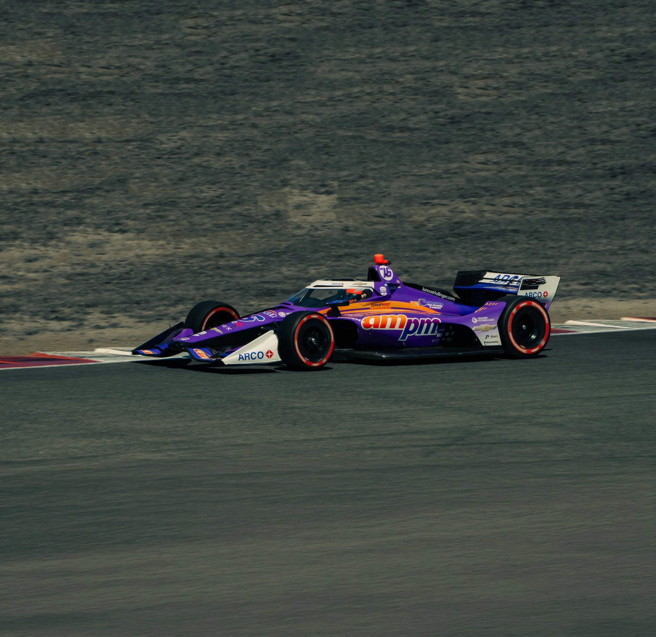 Motorsports race car on a track with a blurred background of gravel or dirt.