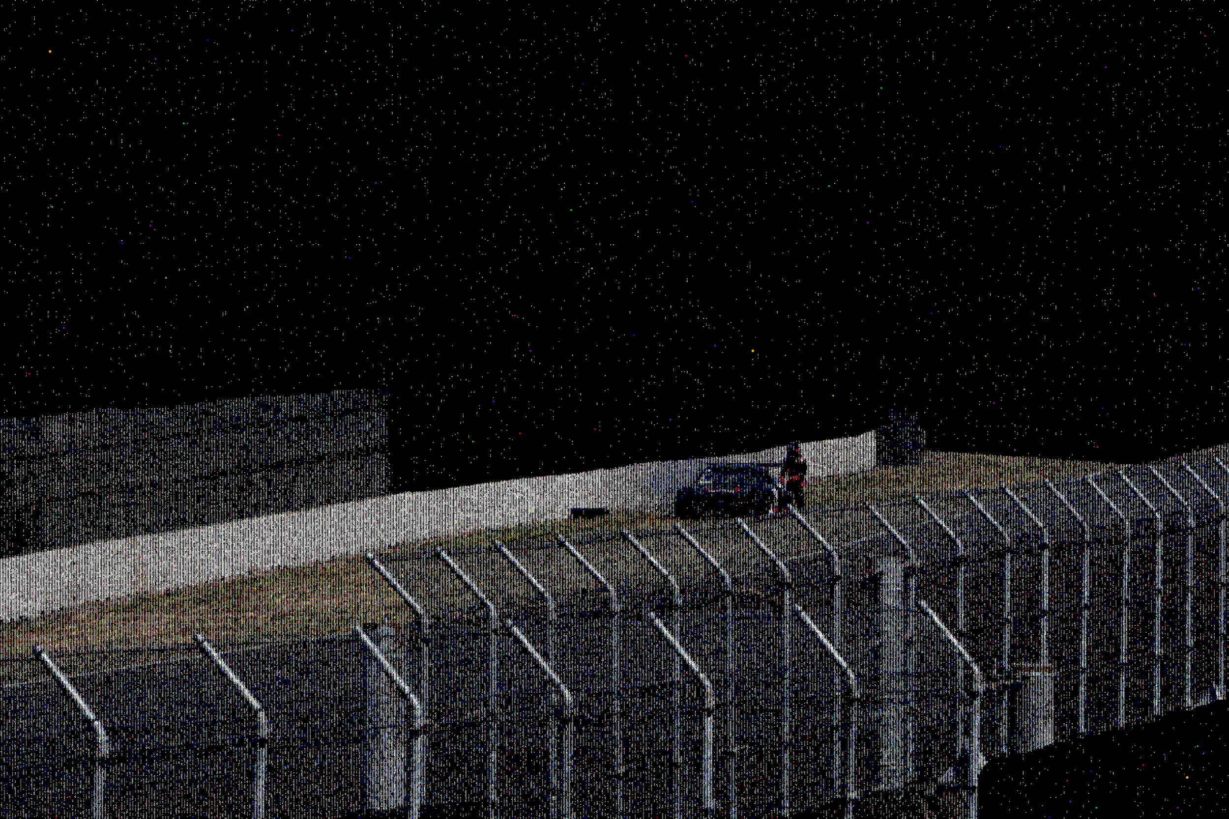 Nighttime scene of a parking lot with a black wall and a roof in the background, under a sky filled with stars.