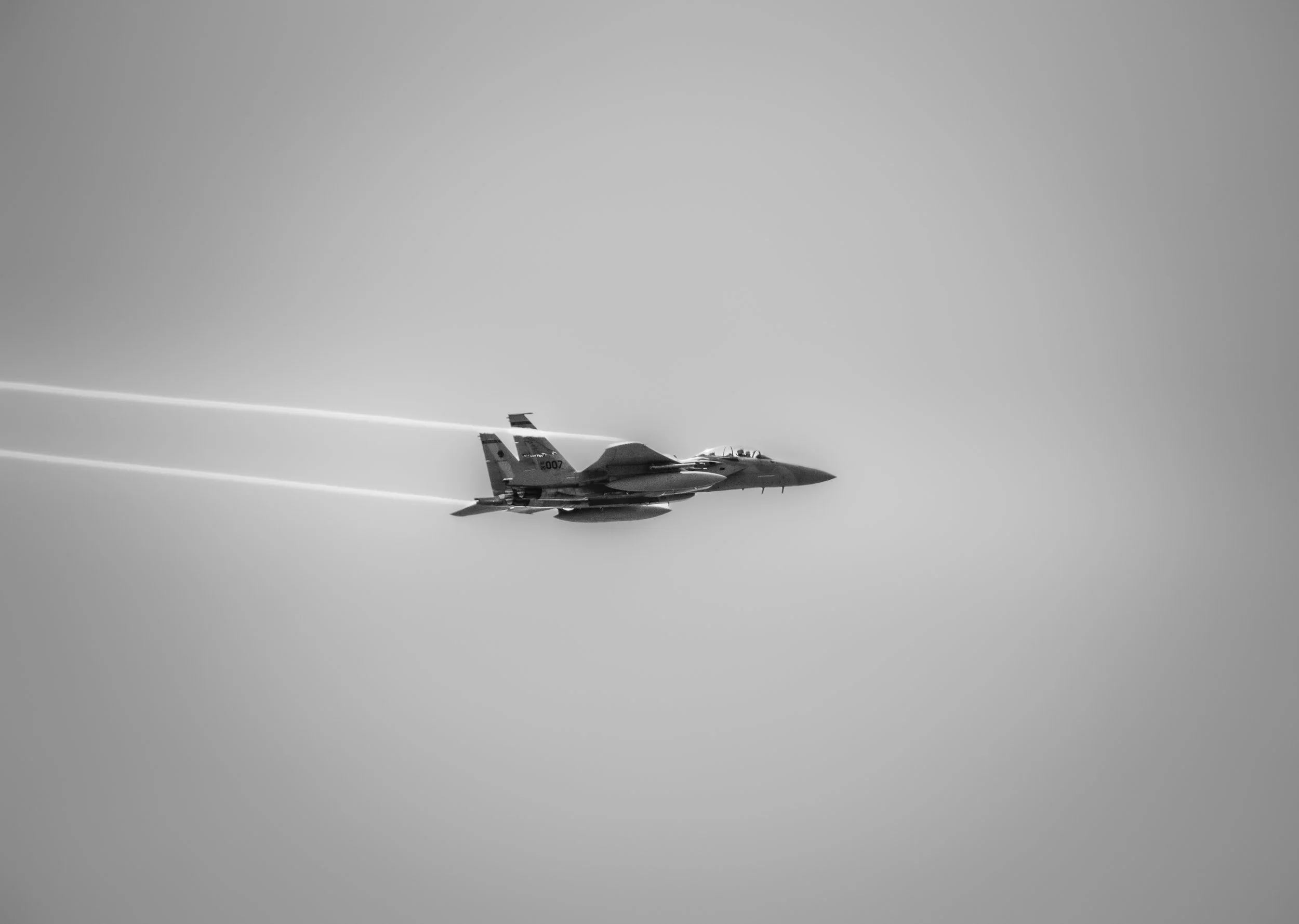 A fighter jet flying in the sky, leaving contrails behind.