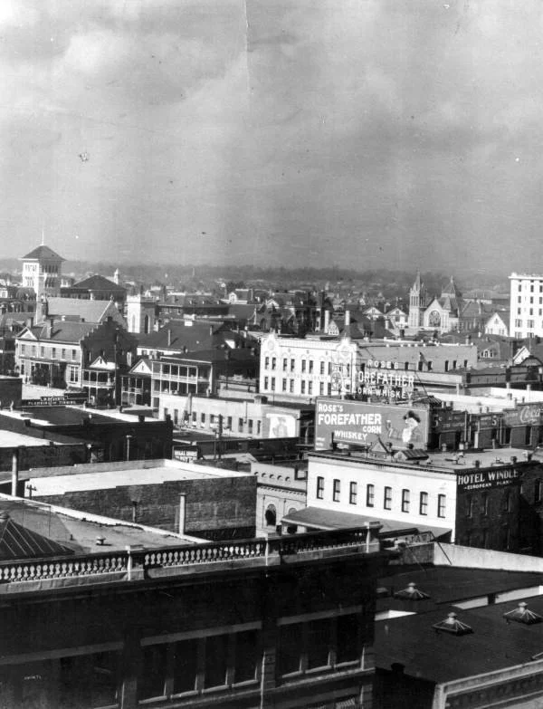 Black-and-white historical photograph of downtown Jacksonville, Florida, showing the city skyline, churches, commercial buildings, rooftop signs, and the Hotel Windle from an elevated viewpoint.