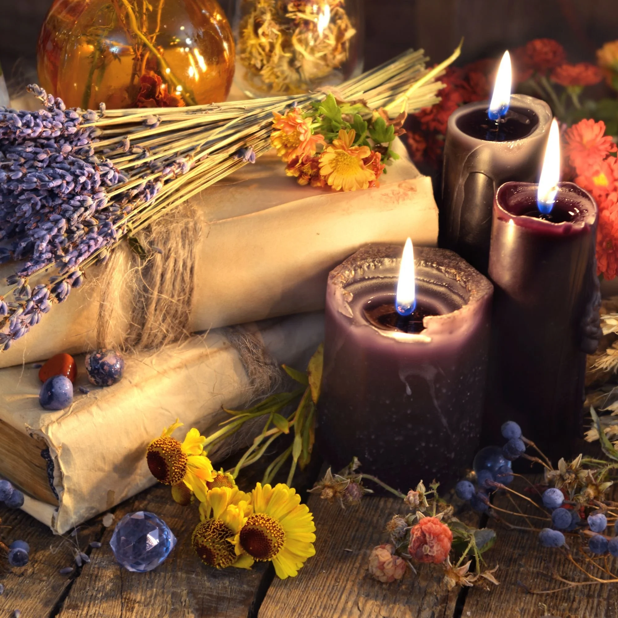 A Dia de los Muertos altar decorated with candles, marigold flowers, dried flowers, a glass jar with flowers, and various colorful decorative items.