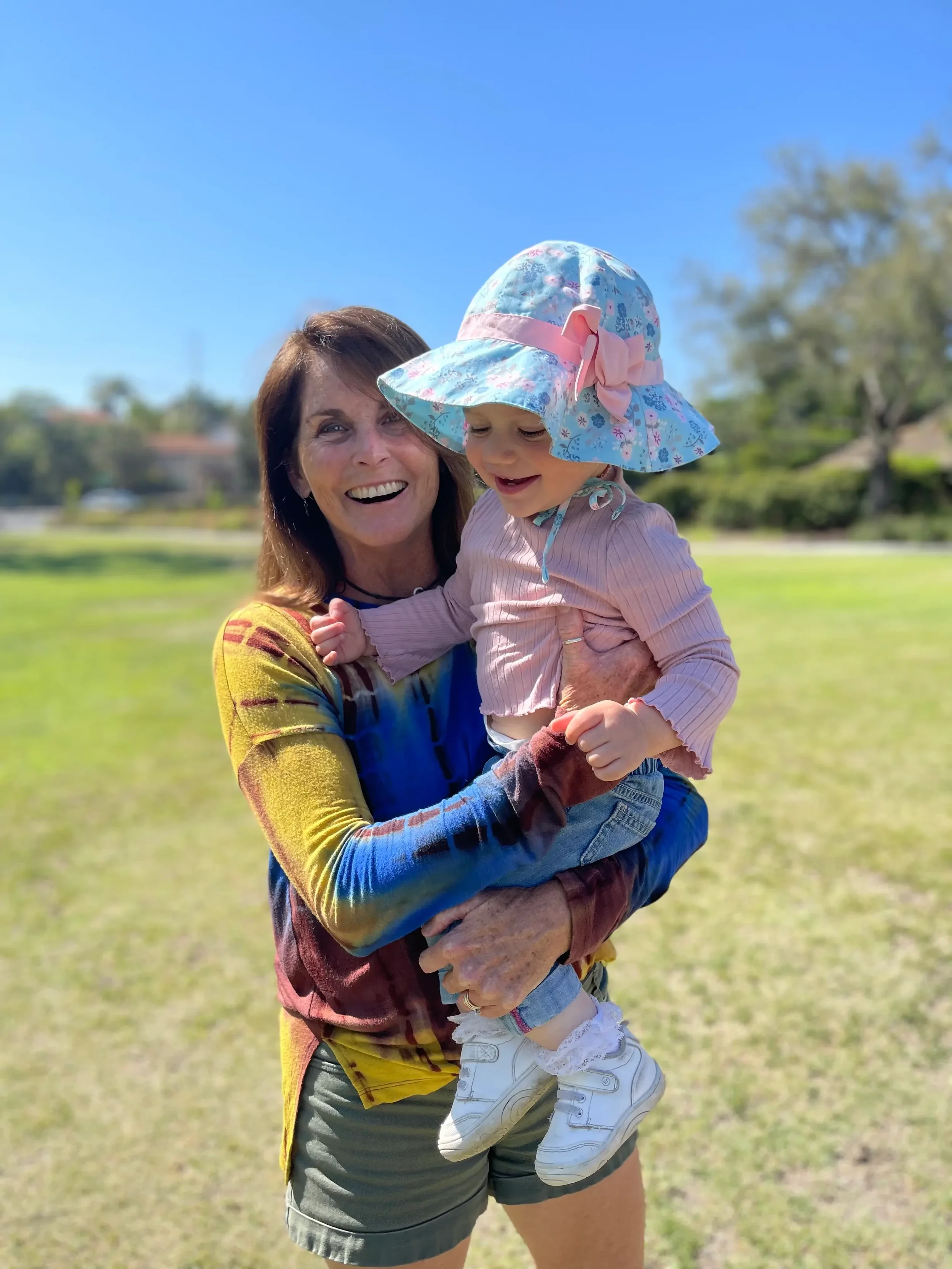 laura-greer-holding-toddler-sun-hat-encinitas-park.webp