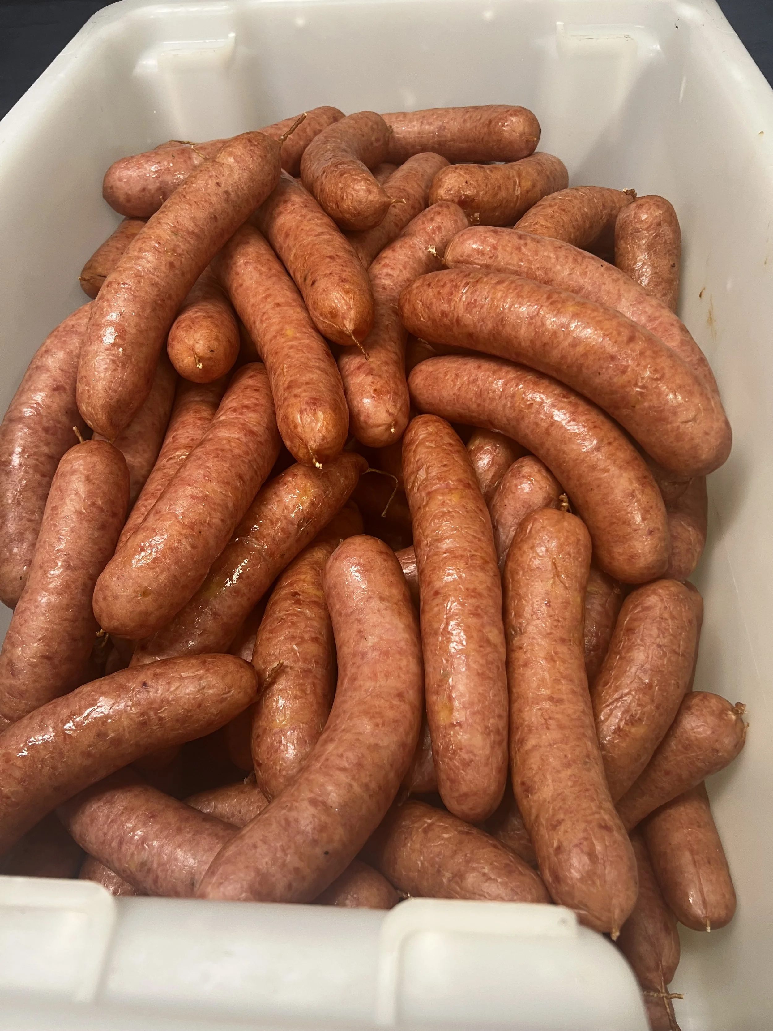 Fresh raw sausages inside a white plastic container.
