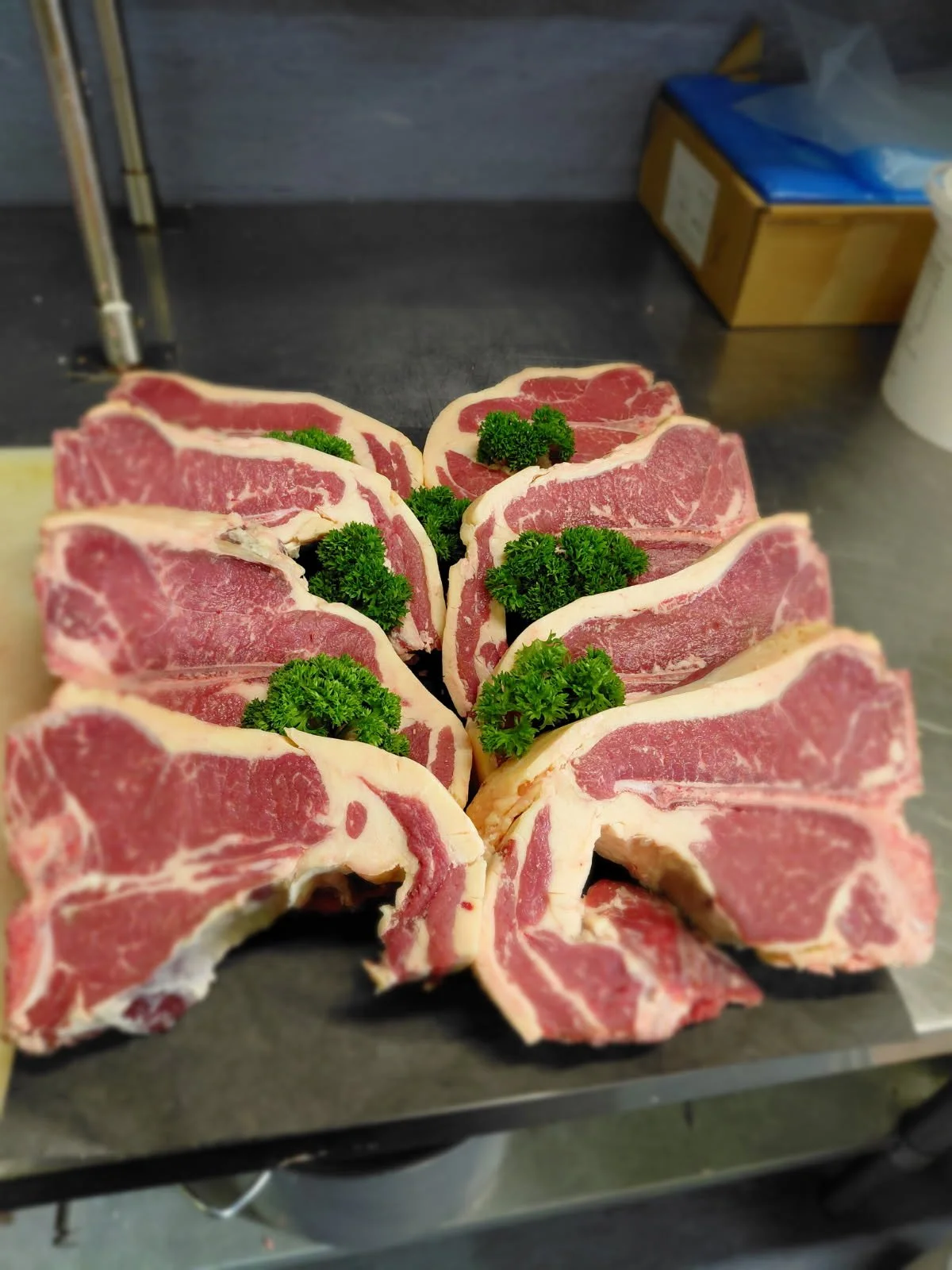 Slices of raw beef steak garnished with parsley on a black cutting board.