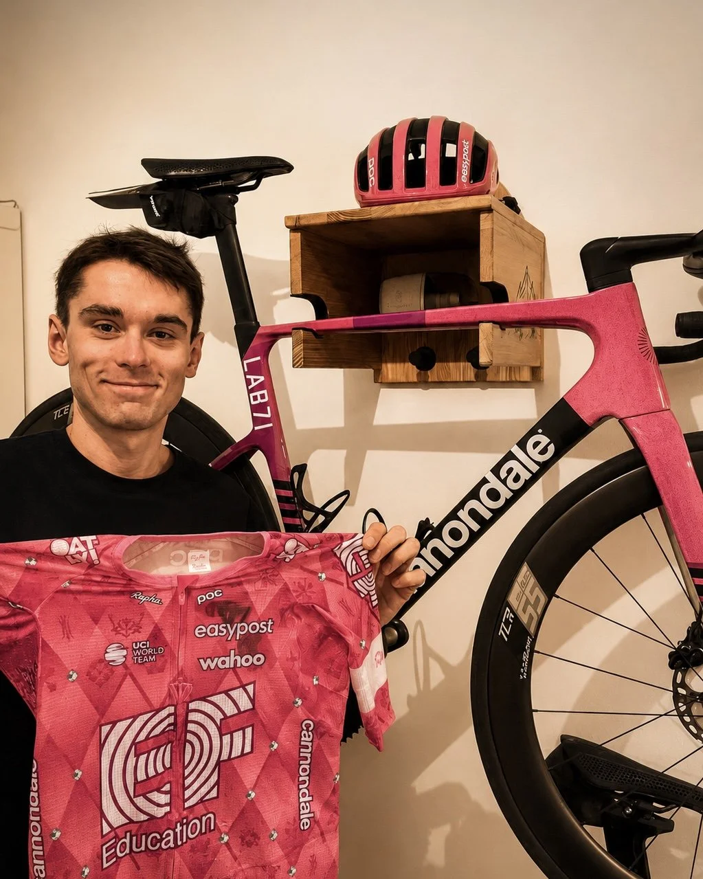 Cycliste professionnel (Alex Baudin) devant son vélo de route installé sur un support vélo mural en bois