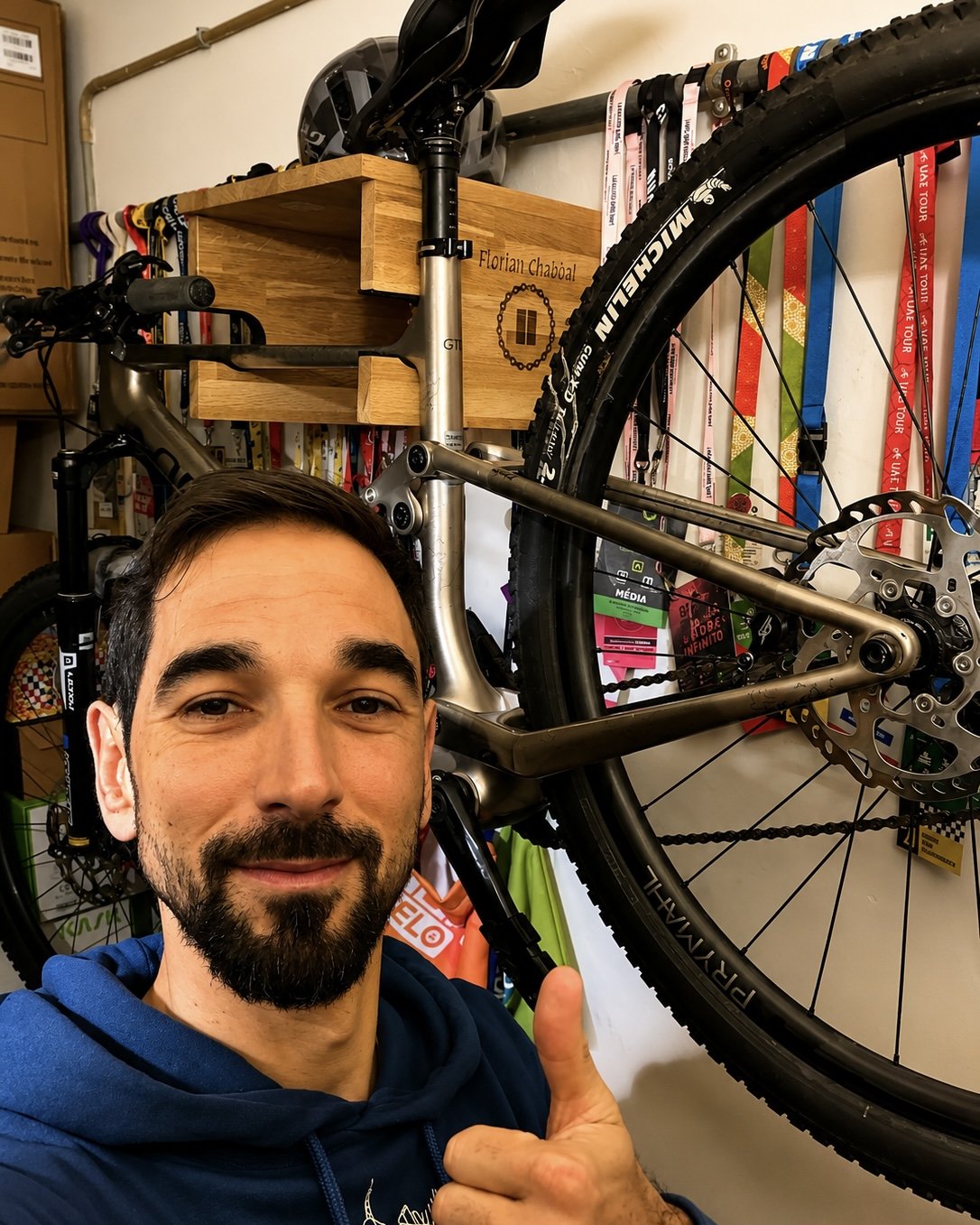 Cycliste professionnel devant son vélo de route installé sur un support vélo mural en bois