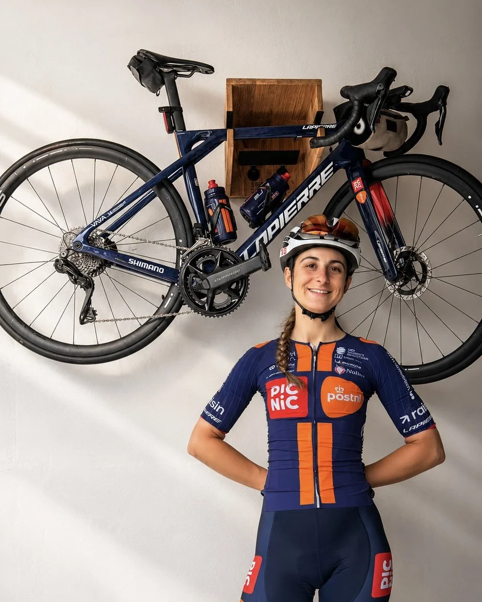 Cycliste professionnelle (Dilixyne Miermont) devant son vélo de route installé sur un support vélo mural en bois