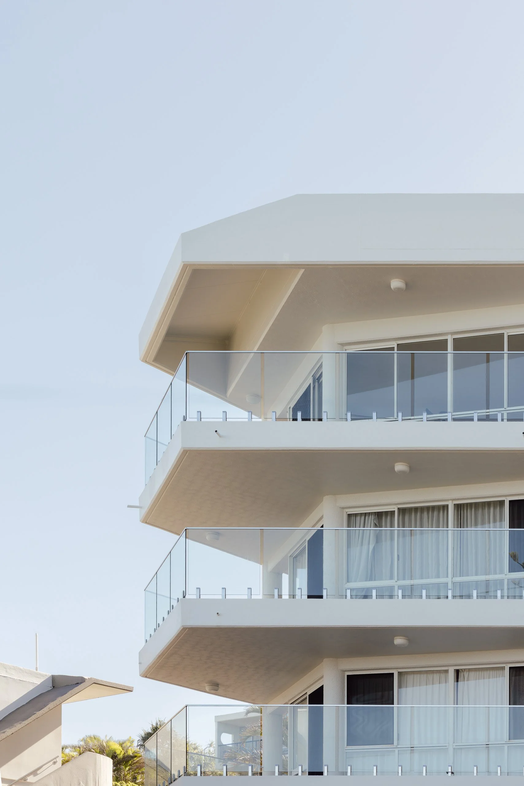 Multi-storey coastal apartment building at Kings Beach with clear glass balustrades across its balconies.