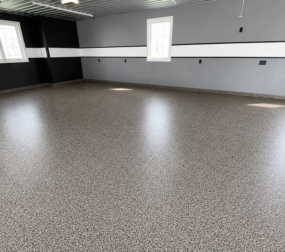 Room with one grey wall, one black wall, a horizontal white stripe across the middle of both walls, and a beige speckled epoxy floor