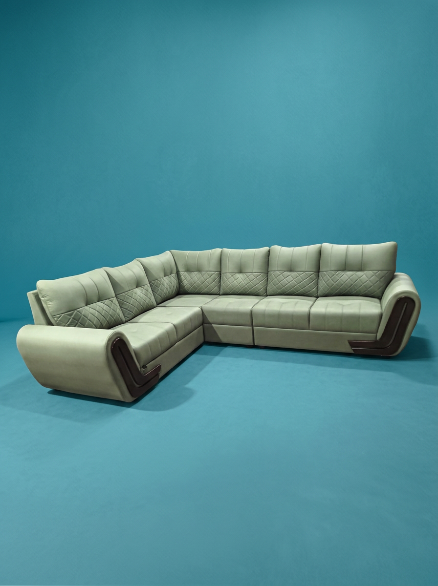 A vintage beige sectional sofa with quilted pattern cushions placed against a plain blue background.
