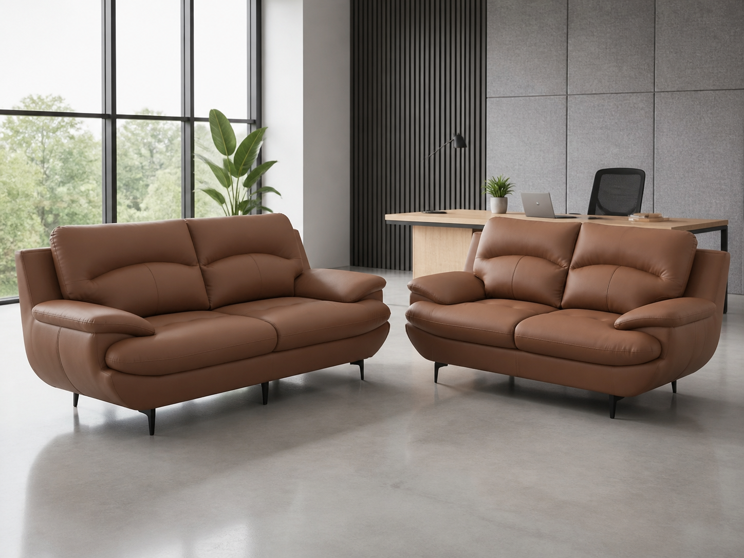Modern office lounge with two brown leather sofas, a large window with greenery outside, a plant, and a workspace with a desk, laptop, and office chair.