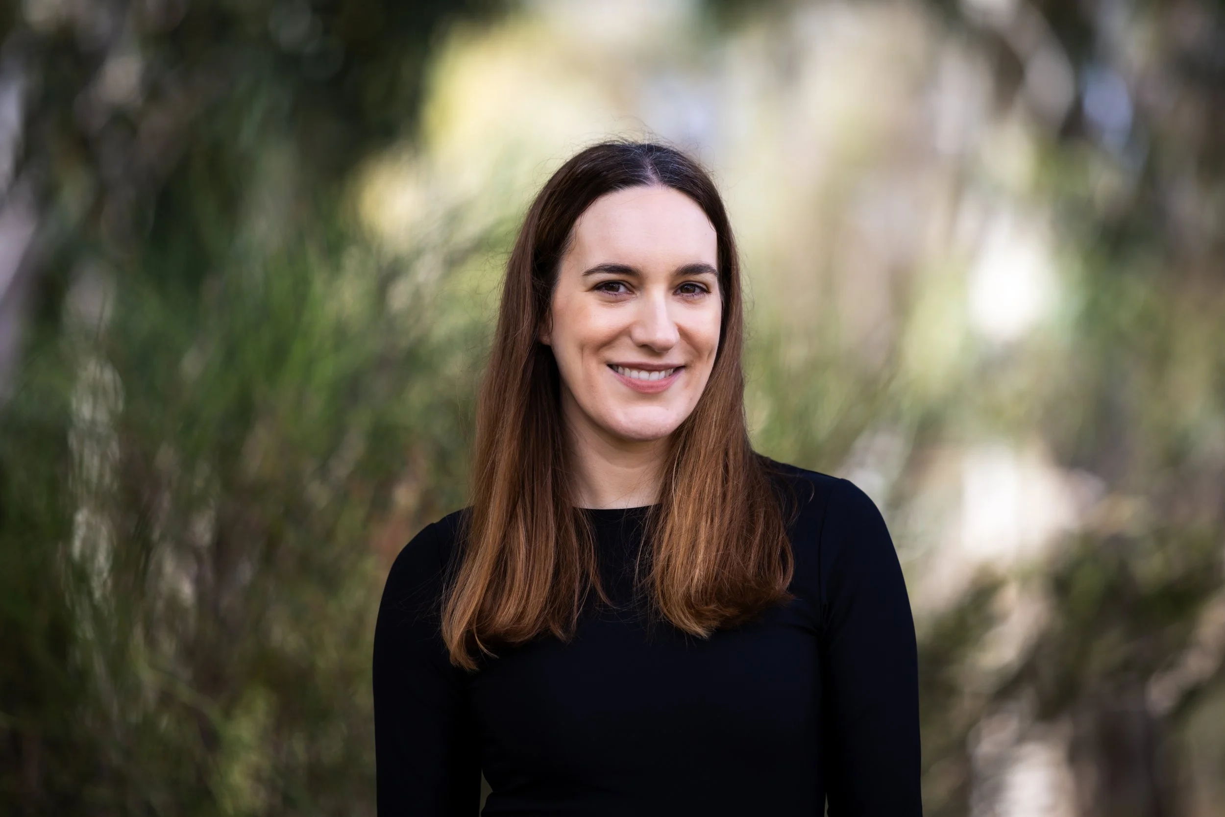 Image of Britt McCarthy, a smiling brunette in a black shirt in front of a naturescape background