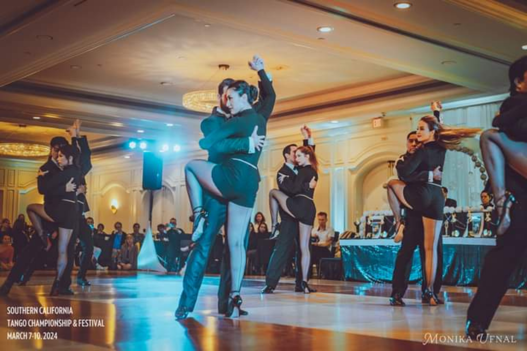 Dancers performing at the Southern California Tango Championship & Festival in March 2024, with couples in black and beige outfits on a dance floor inside a large, elegant ballroom.