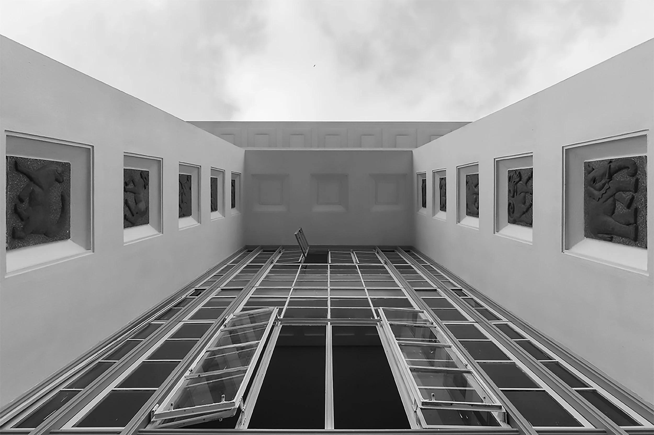 View of a modern high-rise building with glass windows reflecting the sky, taken from below looking upward.