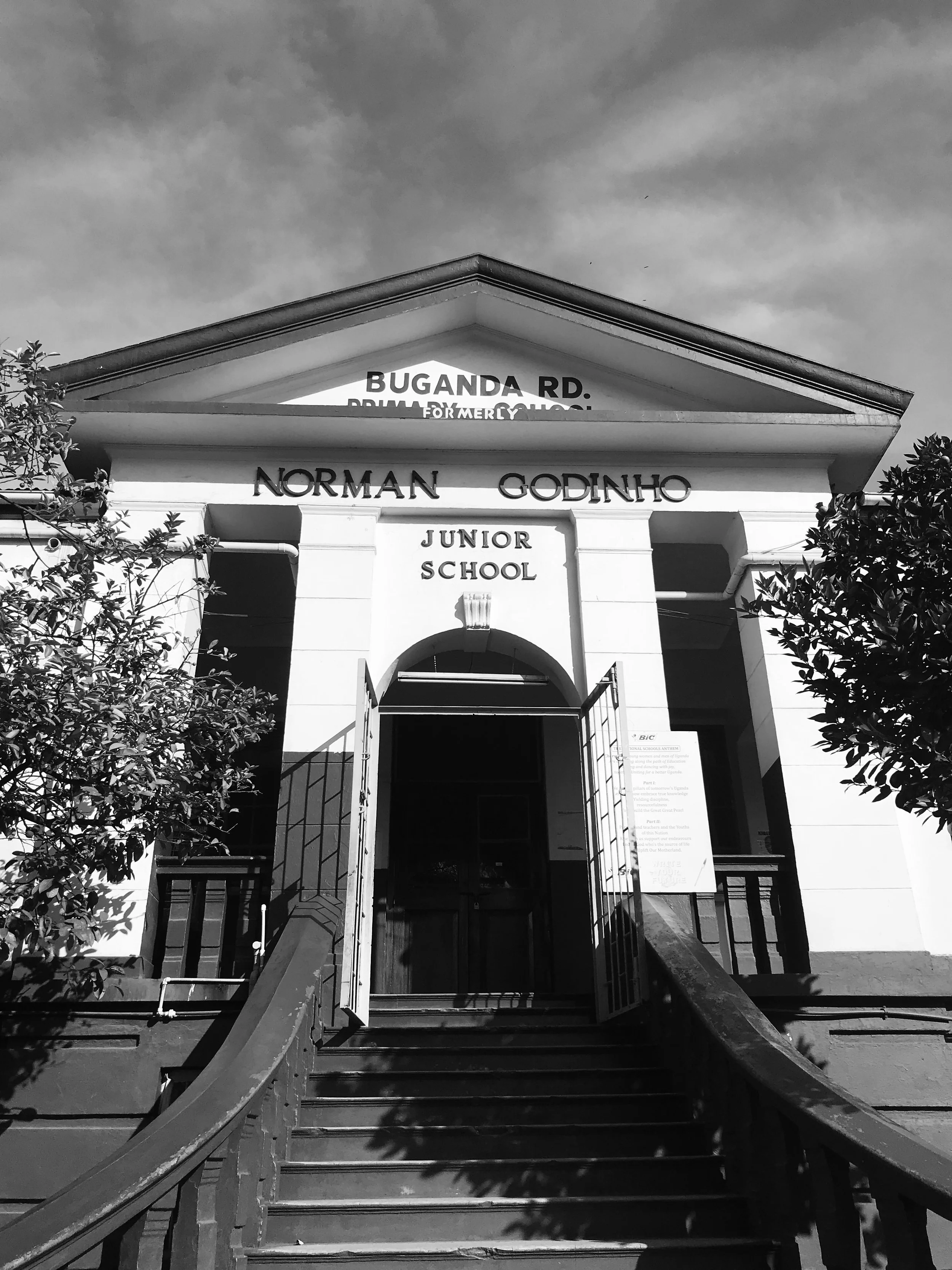 The front entrance of Norman Godinho Junior School with stairs and a gated doorway, and the school name displayed above.